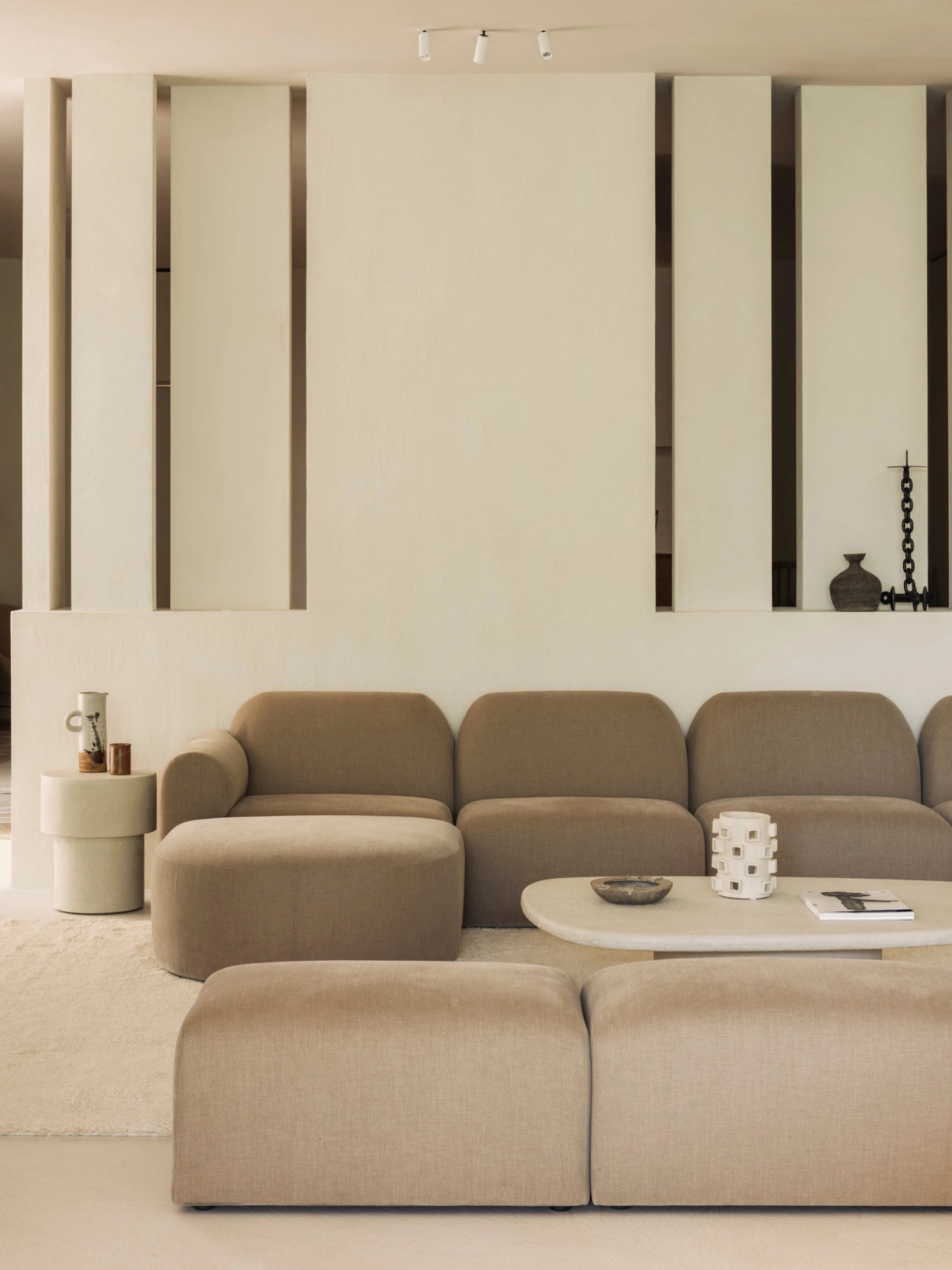 Ethnicraft Bulky Modular Sofa in a light beige, plush fabric, forming a spacious sectional in a contemporary living room. The soft, rounded contours and modular design offer versatile comfort, alongside a modern coffee table and decorative elements.