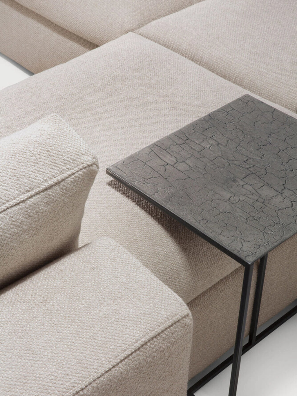 Ethnicraft Mellow Modular Sofa, showcasing the luxurious light beige textured fabric and plush cushions, with a modern dark side table featuring a cracked pattern.