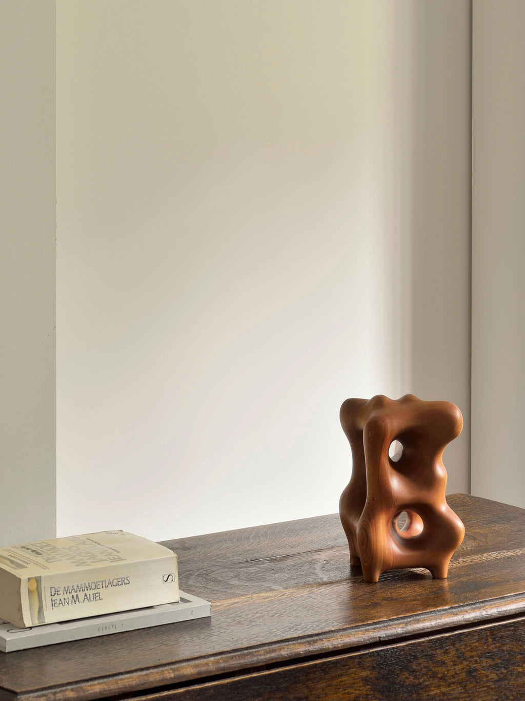 Ethnicraft Natural Organic Sculpture, a sophisticated mahogany wood decorative item with a smooth, polished finish and intricate organic forms, stylishly positioned on a dark wooden chest of drawers.