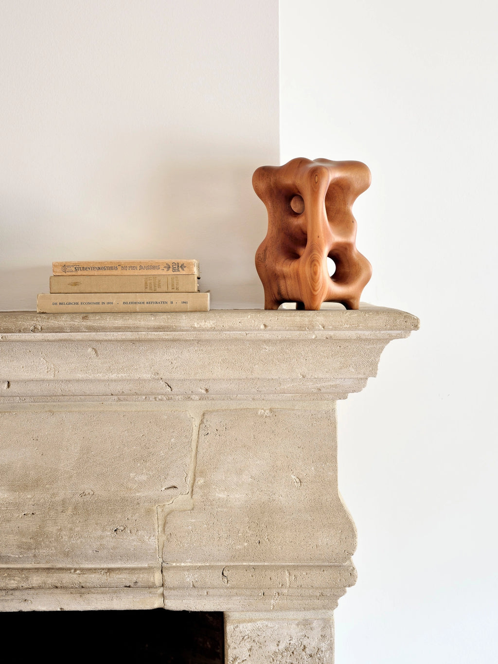Ethnicraft Natural Organic Sculpture, a beautiful mahogany wood accent piece with a rich, warm brown color, featuring a flowing, sculptural design, elegantly placed on a classic stone fireplace mantel.