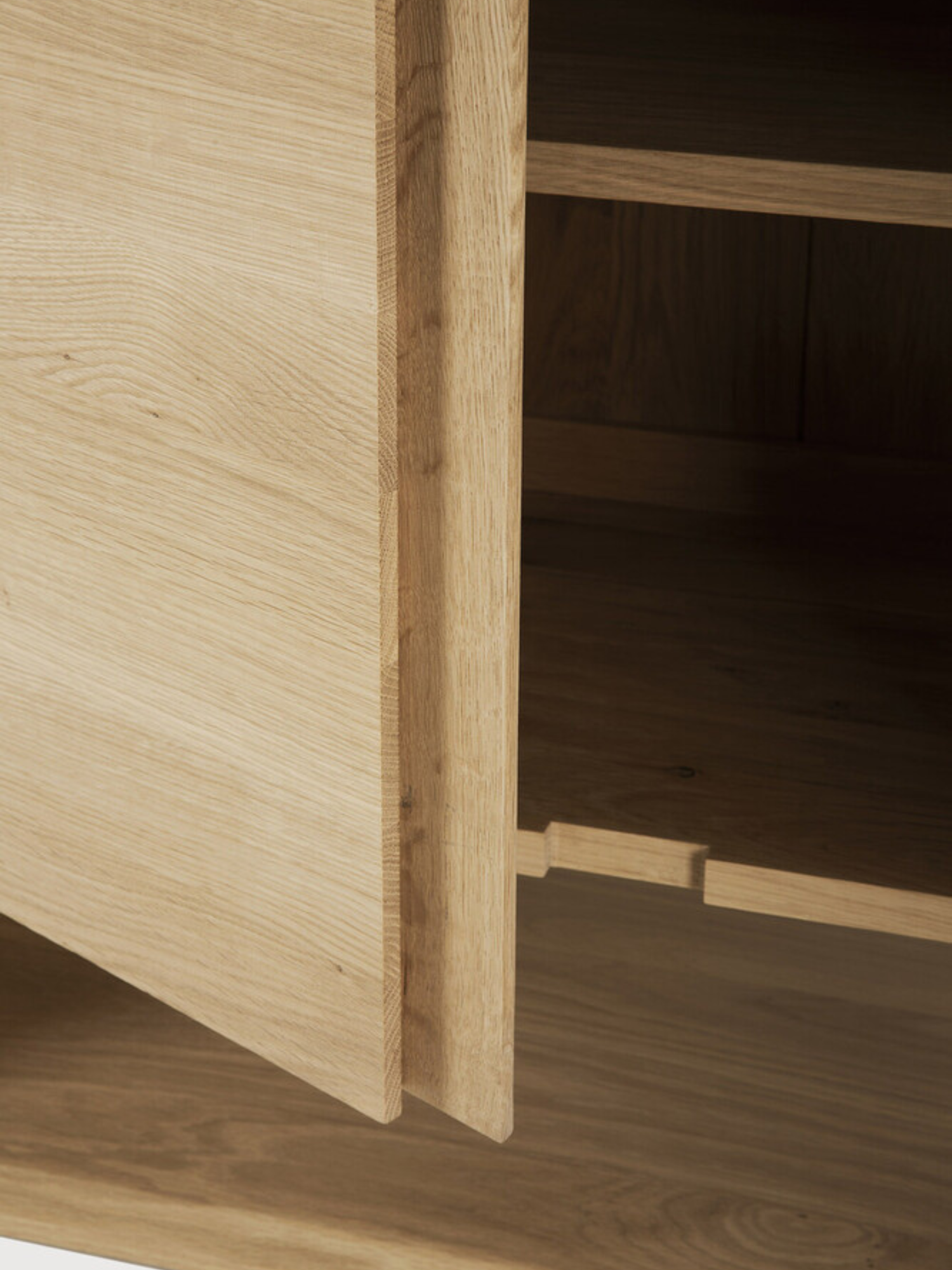 Ethnicraft Nordic Sideboard, a detailed view of an open cabinet door, revealing the interior shelving and the precise, high-quality construction of the natural oak wood.