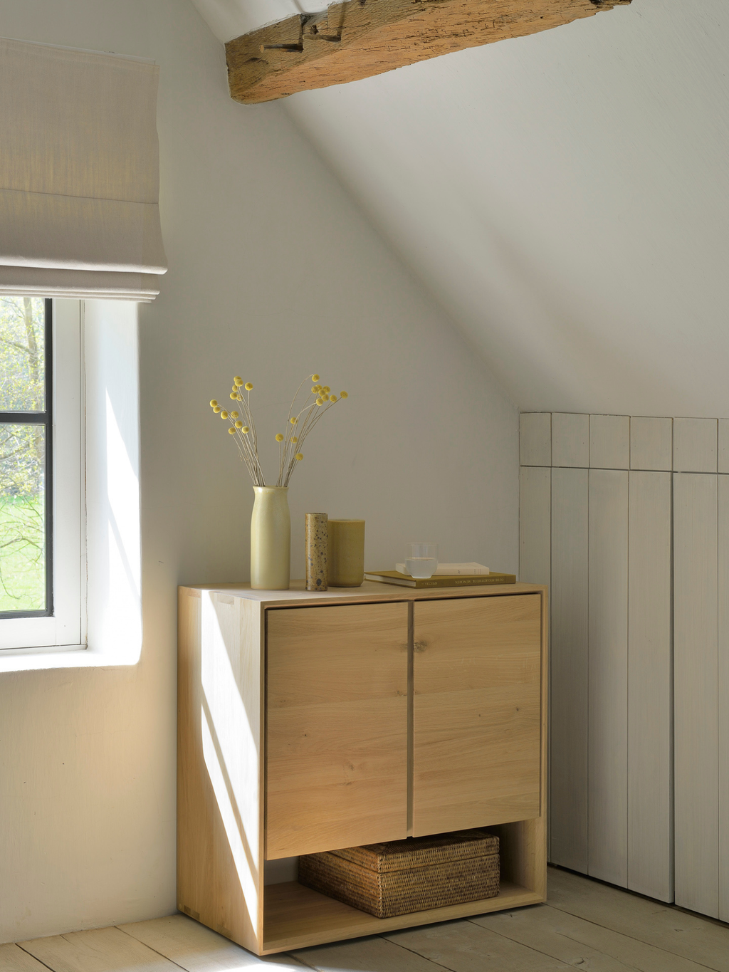 Ethnicraft Nordic Sideboard, crafted from light oak wood, featuring two cabinet doors and an open bottom shelf, styled in a bright, minimalist room with natural light.