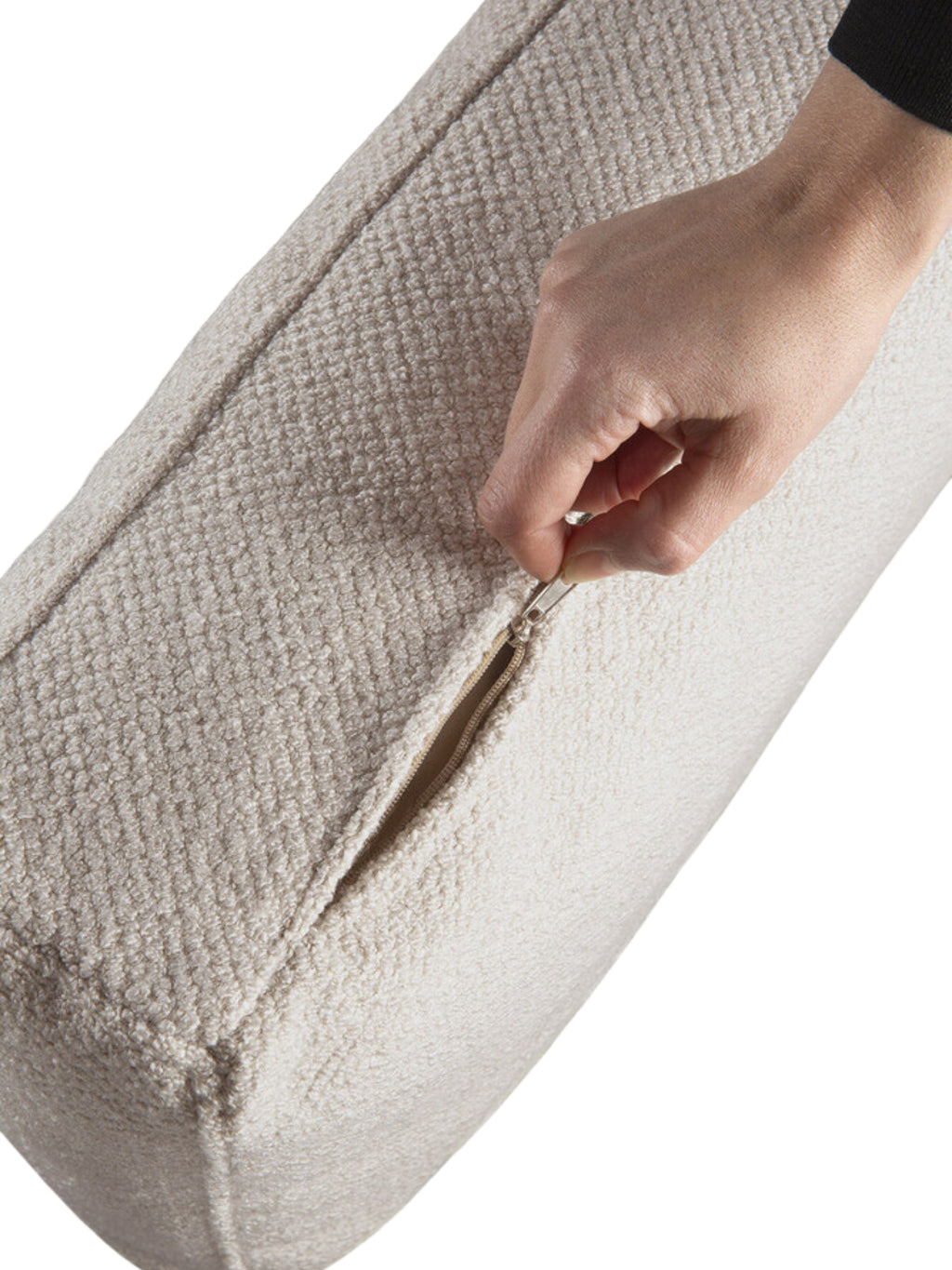 Ethnicraft Mellow Modular Sofa detail, featuring a hand unzipping a cushion cover, revealing the robust, light beige textured fabric and the quality zipper mechanism. This highlights the sofa's removable and washable covers.