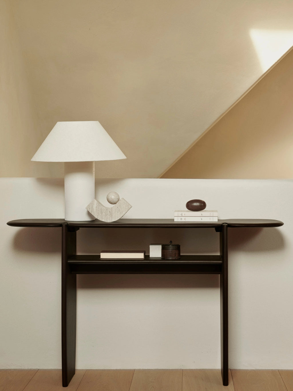 Ethnicraft PI Console in dark brown mahogany, showcasing its sleek, contemporary design with a lower shelf, styled with a white lamp and decorative objects in a warm, inviting room.