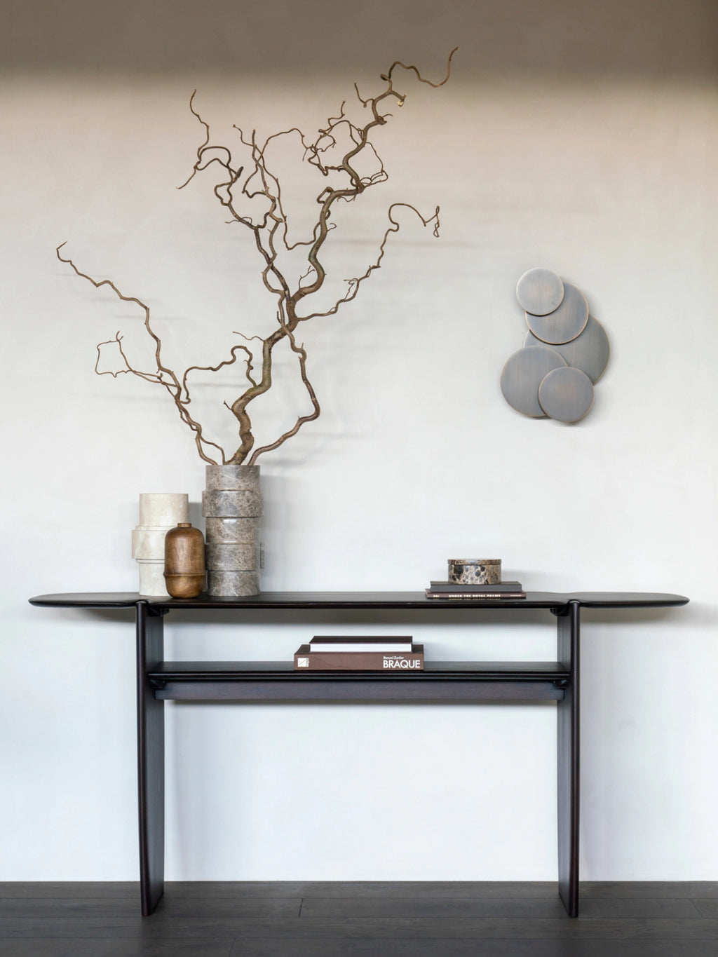 Ethnicraft PI Console in dark brown mahogany wood, featuring an elegant, minimalist design with a lower shelf, styled in a modern living space with decorative vases and books.