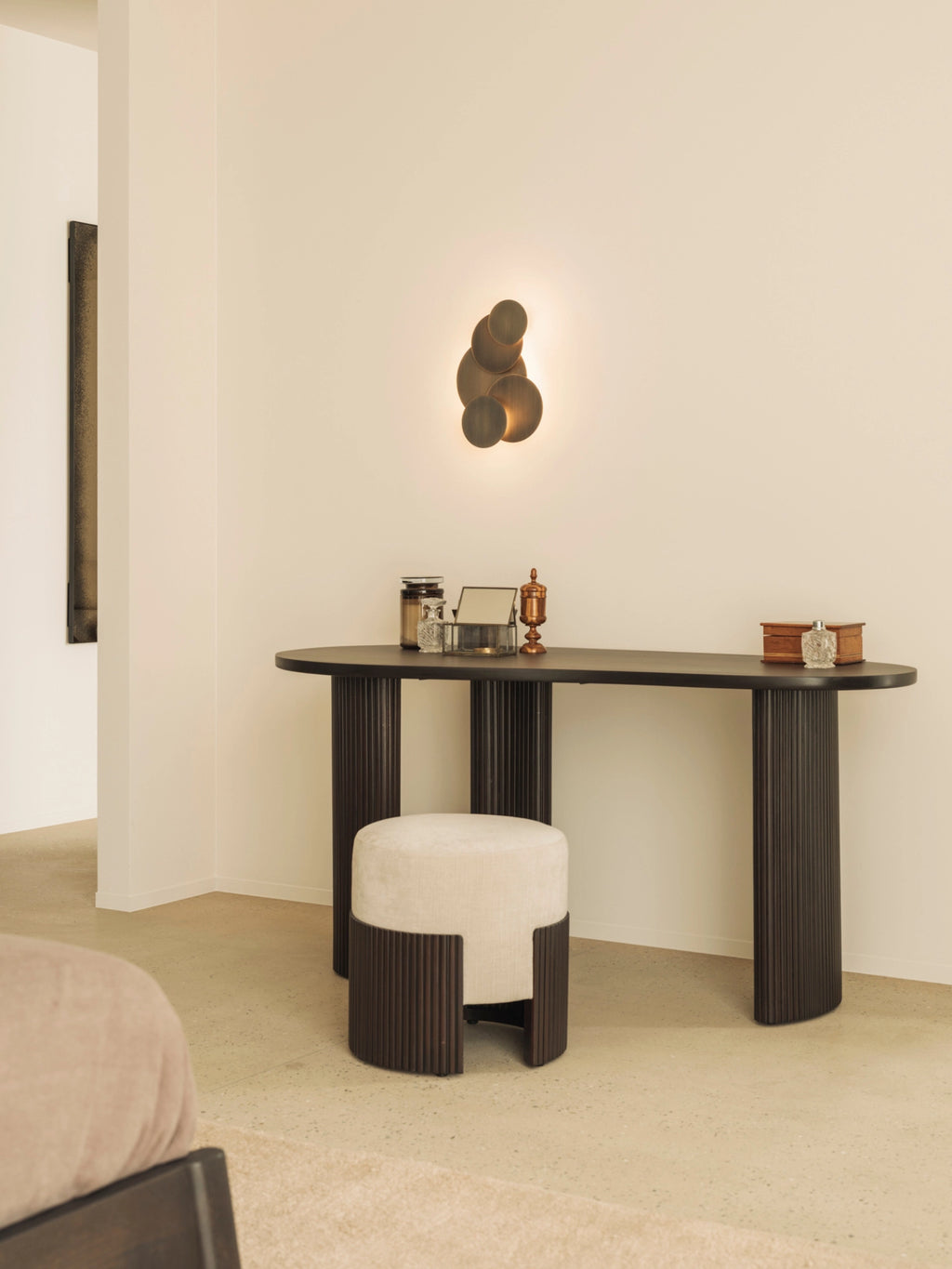 Ethnicraft Roller Max Pouf, 45cm tall, in a sophisticated mahogany finish with a light beige top. Styled as a chic vanity stool in a modern bedroom setting with a dark wood desk.