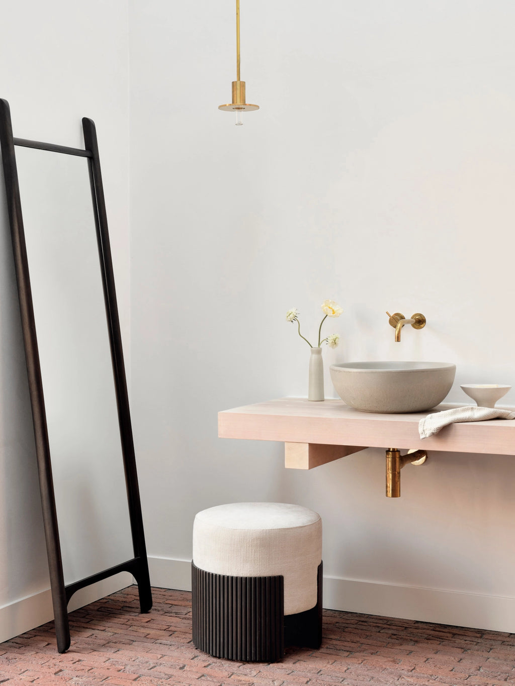 Ethnicraft Roller Max Pouf, 45cm tall, in mahogany and light beige, used as a stylish bathroom stool. Its elegant design complements the contemporary sink and mirror in a minimalist setting.