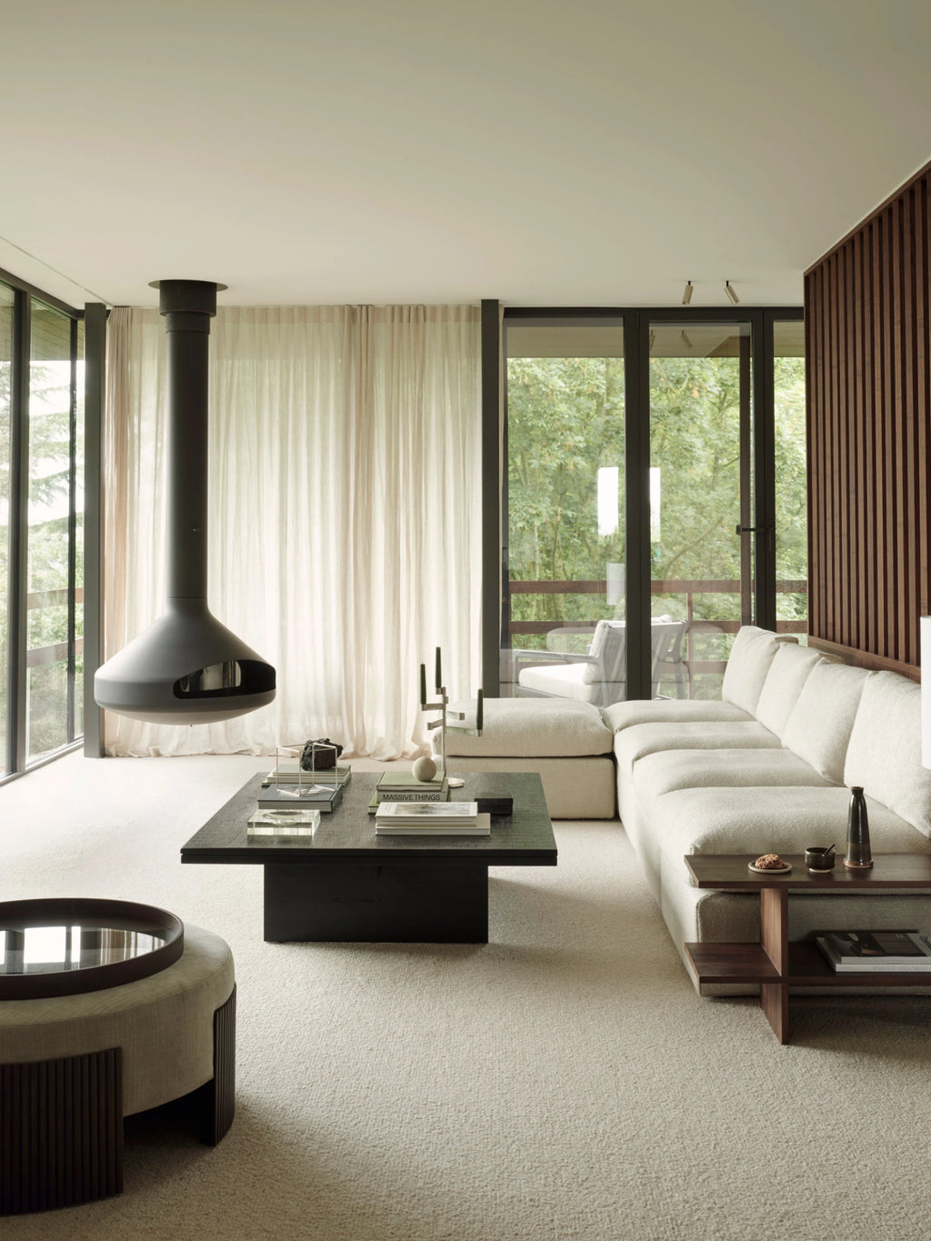 Ethnicraft Roller Max Pouf, 85cm wide, in mahogany, positioned in a spacious, contemporary living room with a large sectional sofa and a sleek black coffee table, highlighting its versatile design.