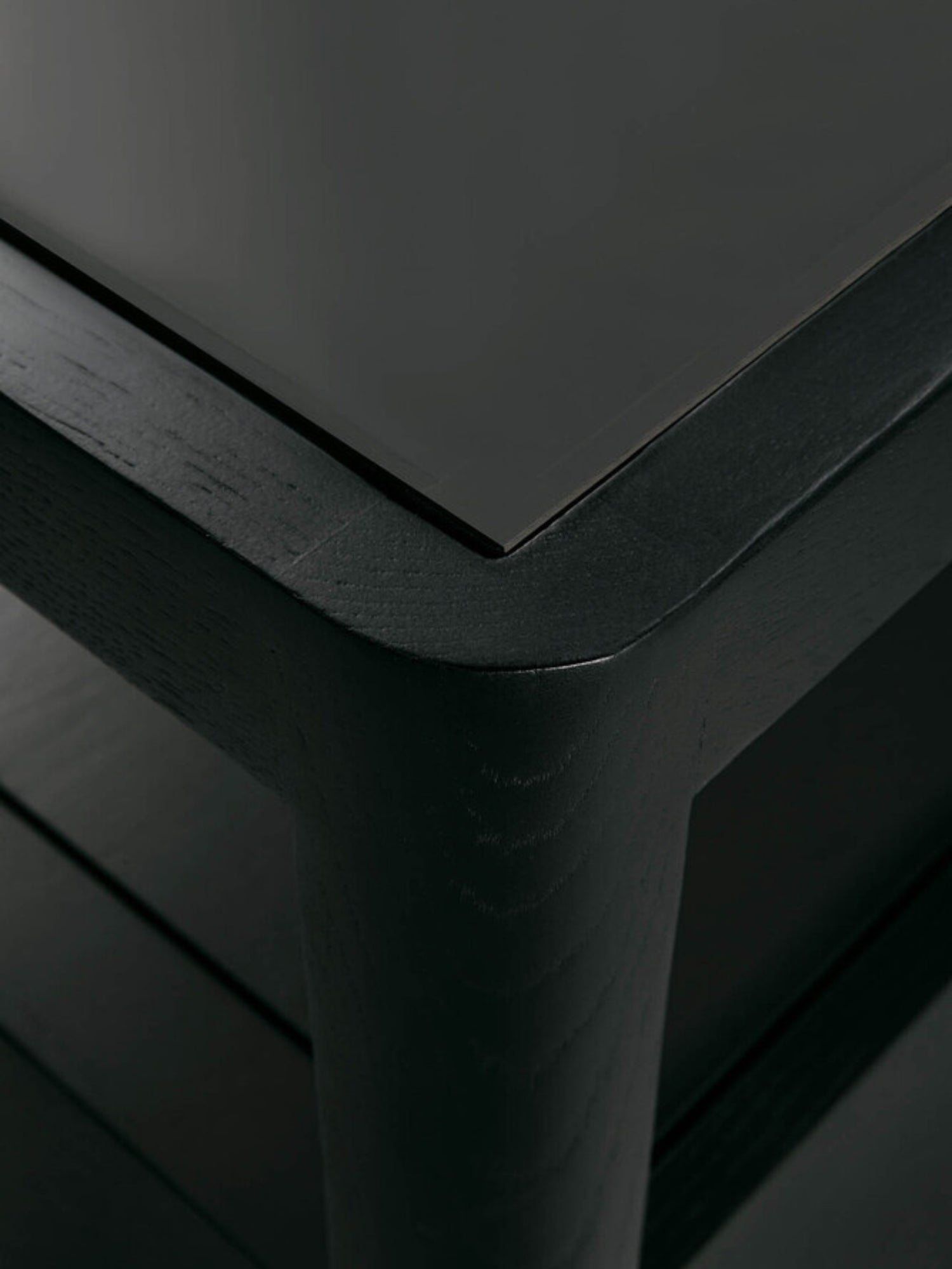 Ethnicraft Spindle Dresser in black oak, highlighting the elegant corner detail with a smooth glass top and robust, dark wooden frame, offering a premium, modern look.