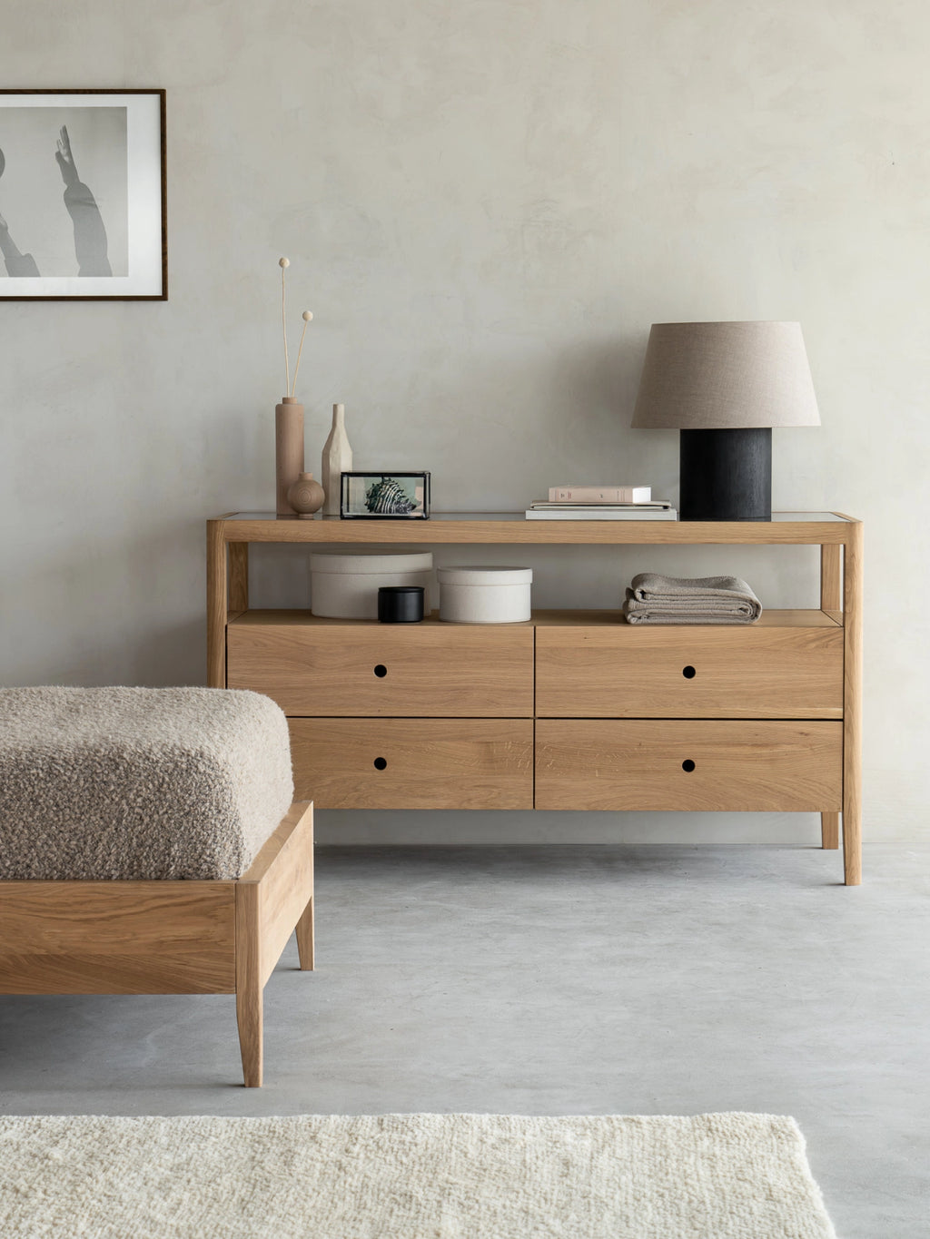 Ethnicraft Spindle Dresser in natural oak, beautifully integrated into a contemporary living space, adorned with a lamp, vases, and books, creating a stylish vignette.