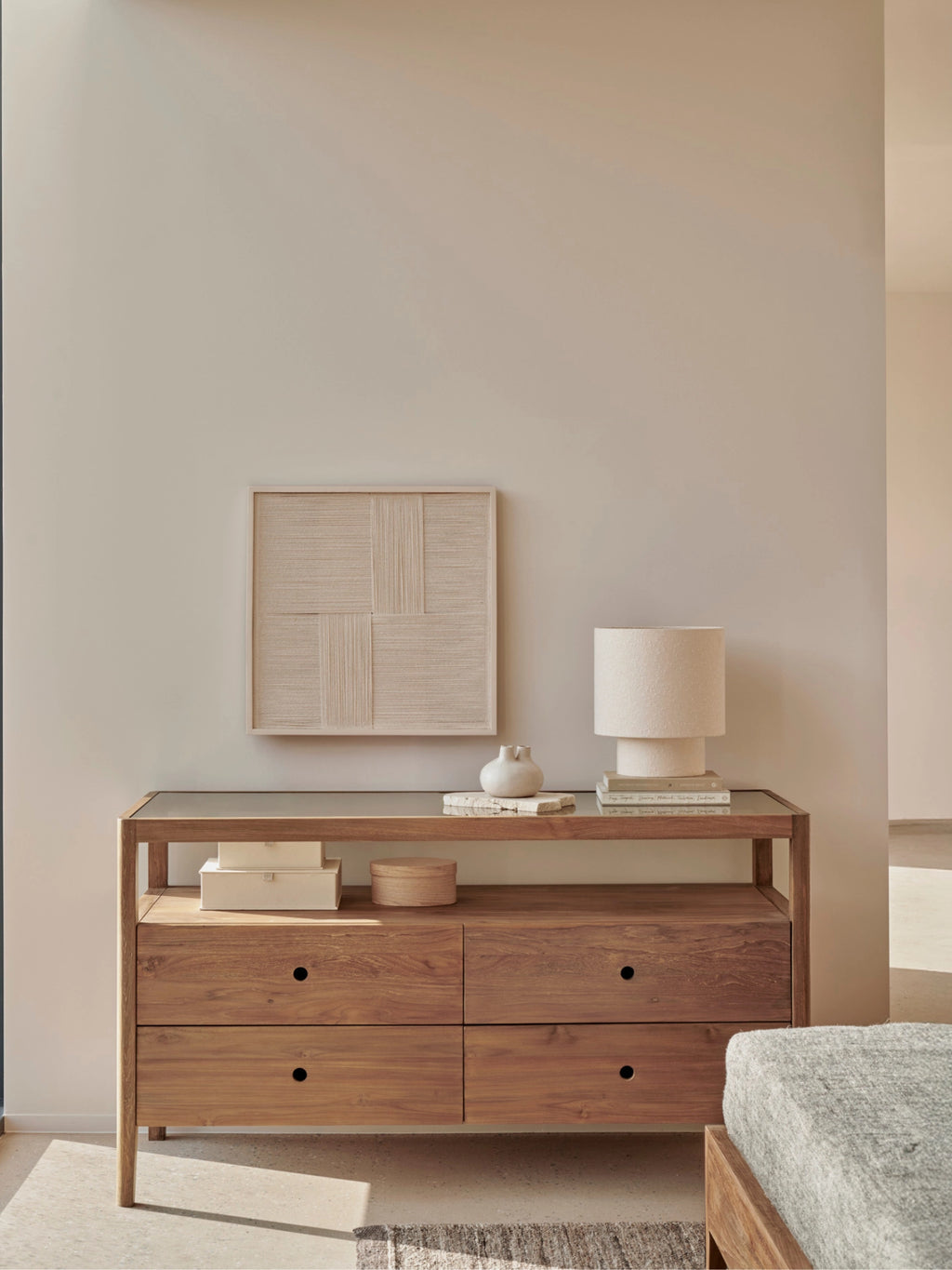 Ethnicraft Spindle Dresser in reclaimed teak, styled in a modern bedroom with a woven art piece, white lamp, and decorative boxes, creating a serene, elegant ambiance.