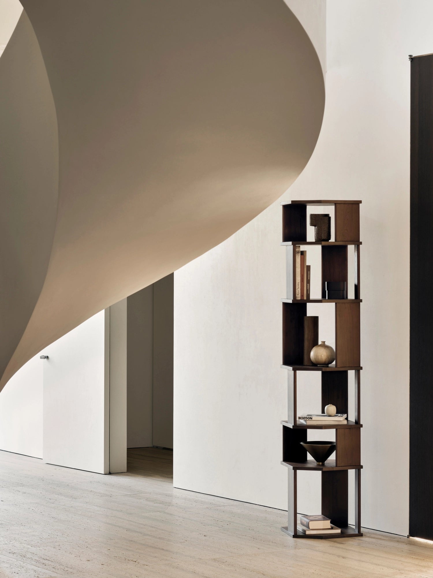 Ethnicraft Stairs Column in rich dark brown teak, a modern modular shelving unit with open cubbies, styled with decorative objects in a contemporary interior with a curved wall.