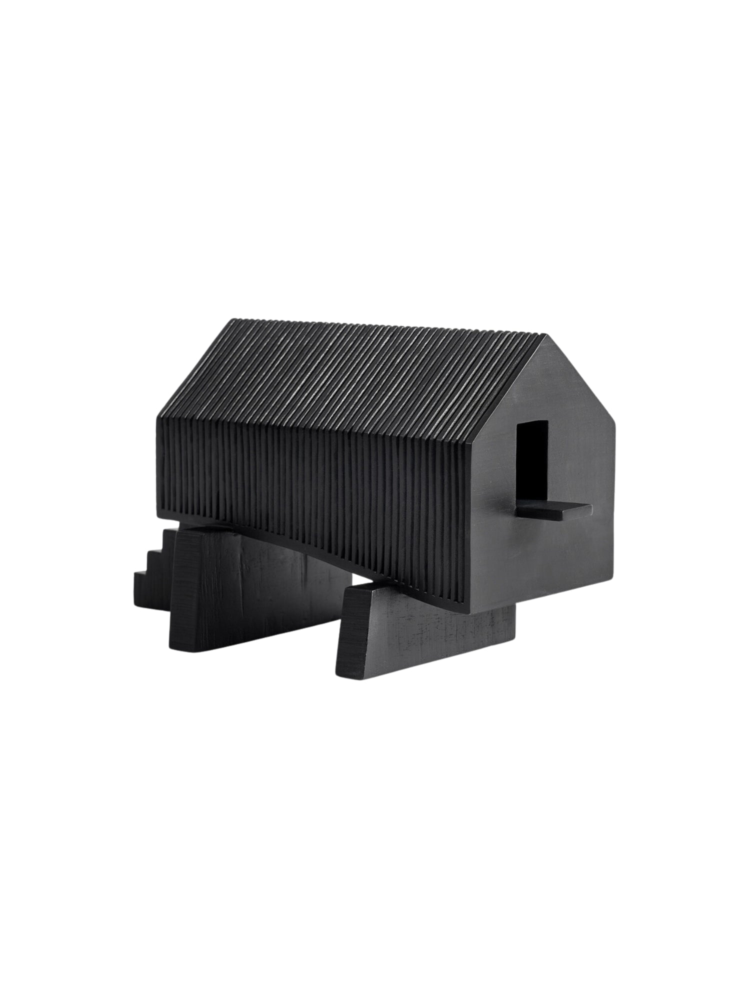 Ethnicraft Stilt House Object. Side view of the contemporary dark black wooden house sculpture, showcasing its distinctive ribbed design, elevated base, and integrated stairs, presented on a clean white background.