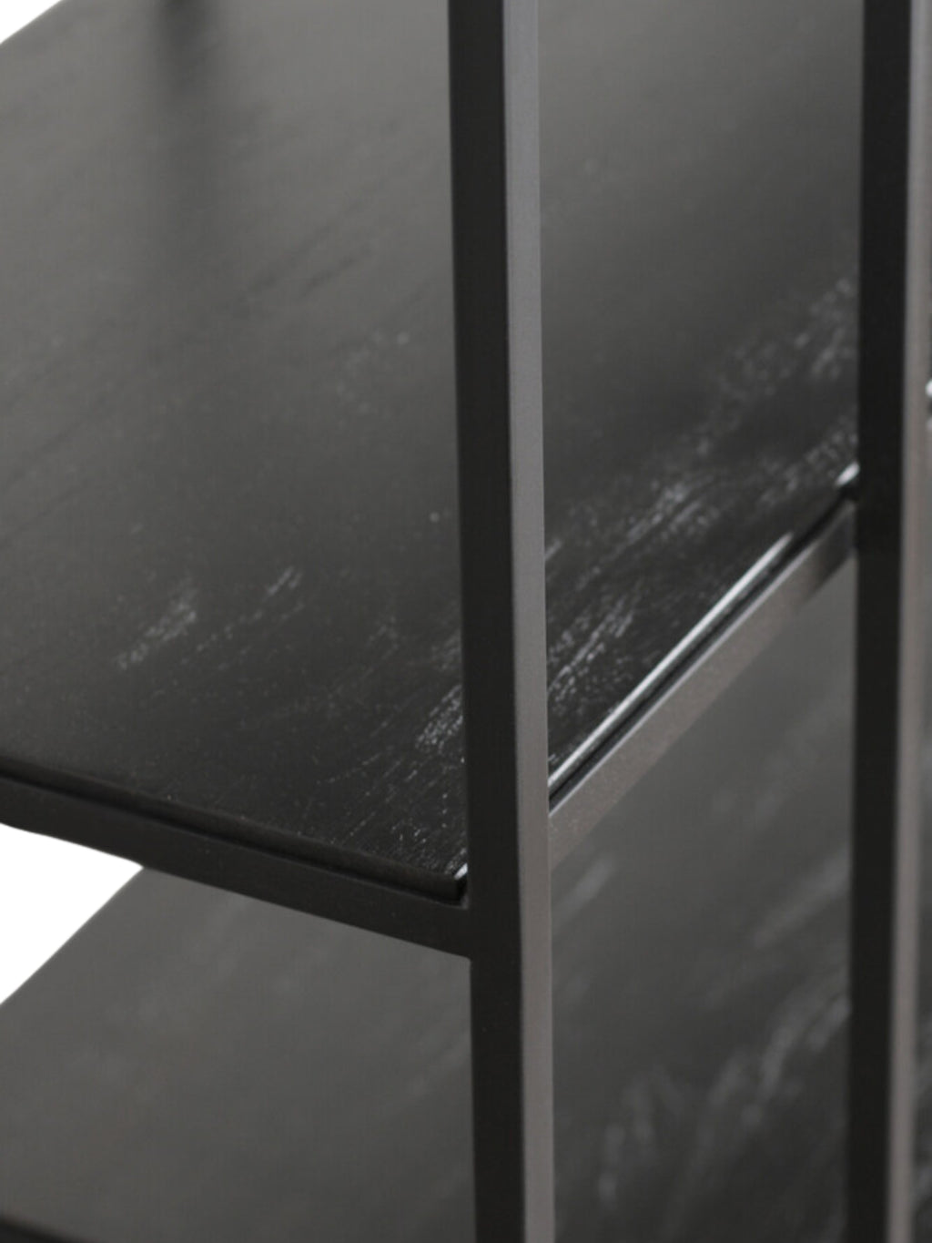 Ethnicraft Studio Rack, a close-up detail of the black teak shelves, showcasing the subtle texture and rich, dark finish. The sturdy metal frame is also visible, displayed on a white background.