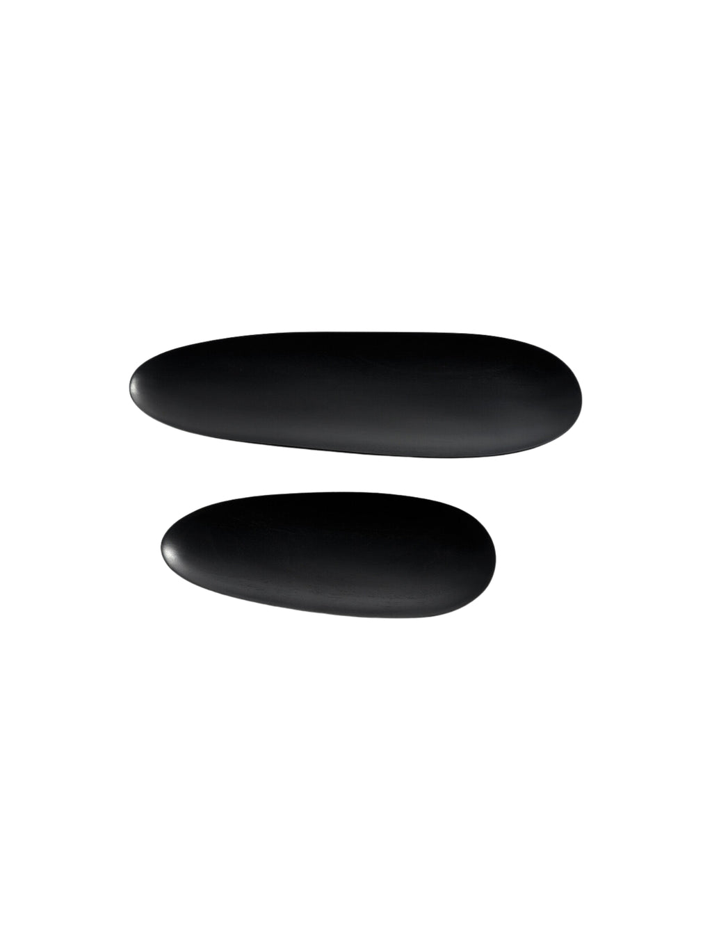 Ethnicraft Thin Oval Boards Set in mahogany black, featuring two distinctively sized, dark oval boards with a smooth, matte finish, arranged parallel to each other, isolated on a bright white background, emphasizing their elegant simplicity.
