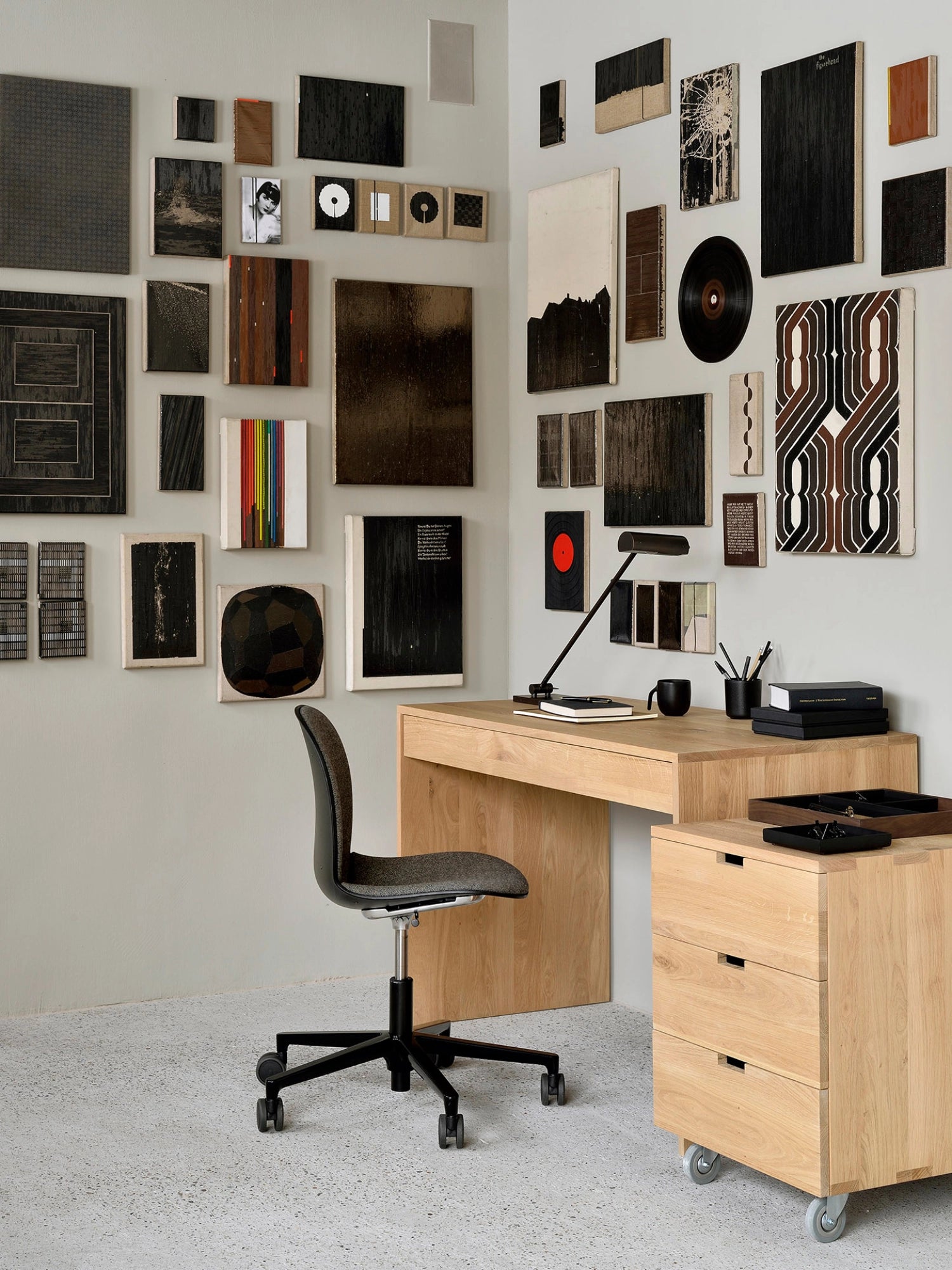 Ethnicraft Wave Desk, a stylish solid oak desk, integrated into a chic home office setting with a black office chair and diverse wall art, showcasing its warm wood tones and functional design.