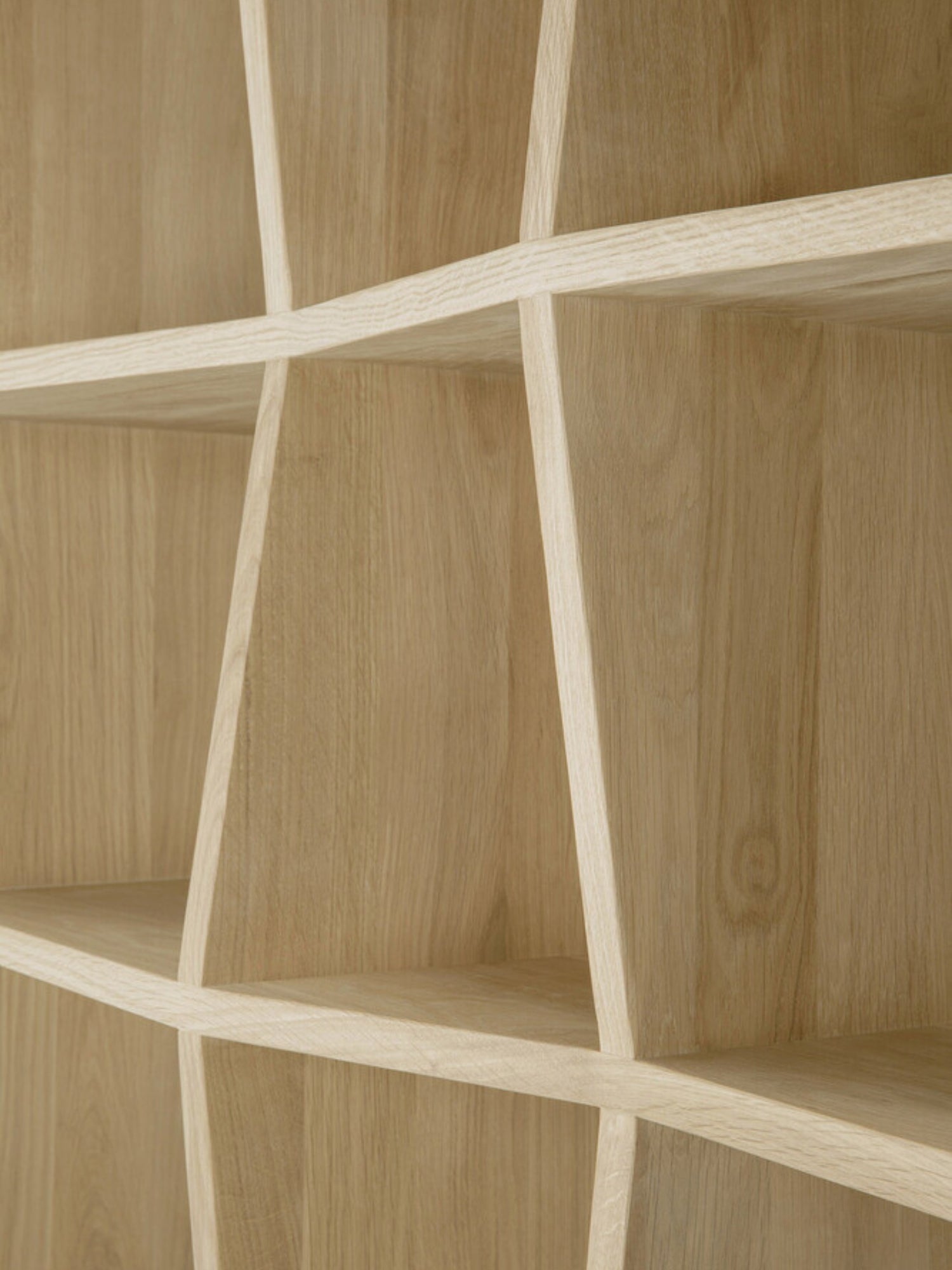 Ethnicraft Z Rack, a close-up detail of the natural light oak wood shelving unit, showing the intricate, angular Z-shaped partitions and smooth wood grain texture.