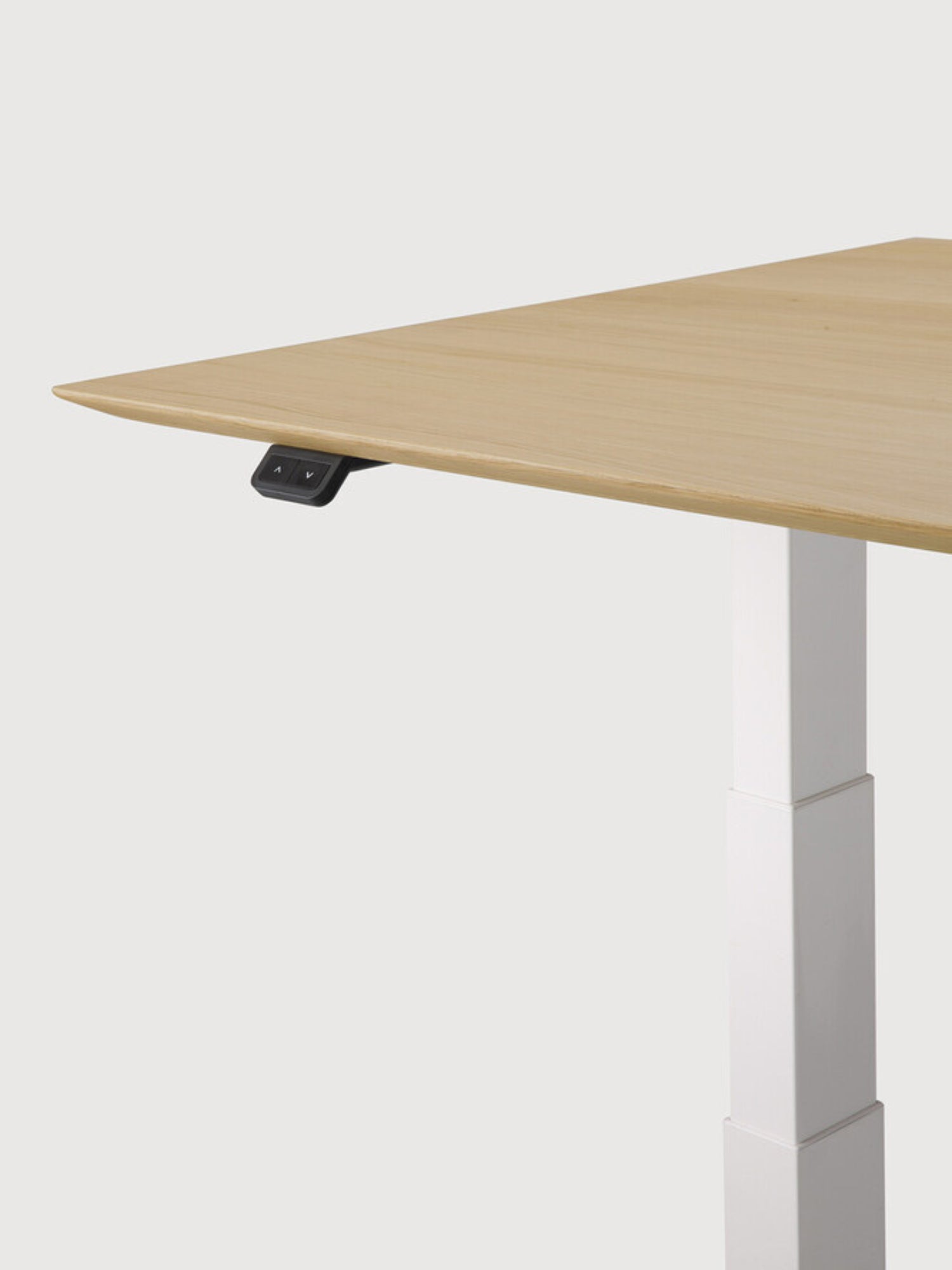 Ethnicraft Bok Adjustable Desk, a detailed close-up of the light oak tabletop edge and the integrated black control panel for height adjustment. The smooth wood texture and crisp white leg detail emphasize premium craftsmanship.