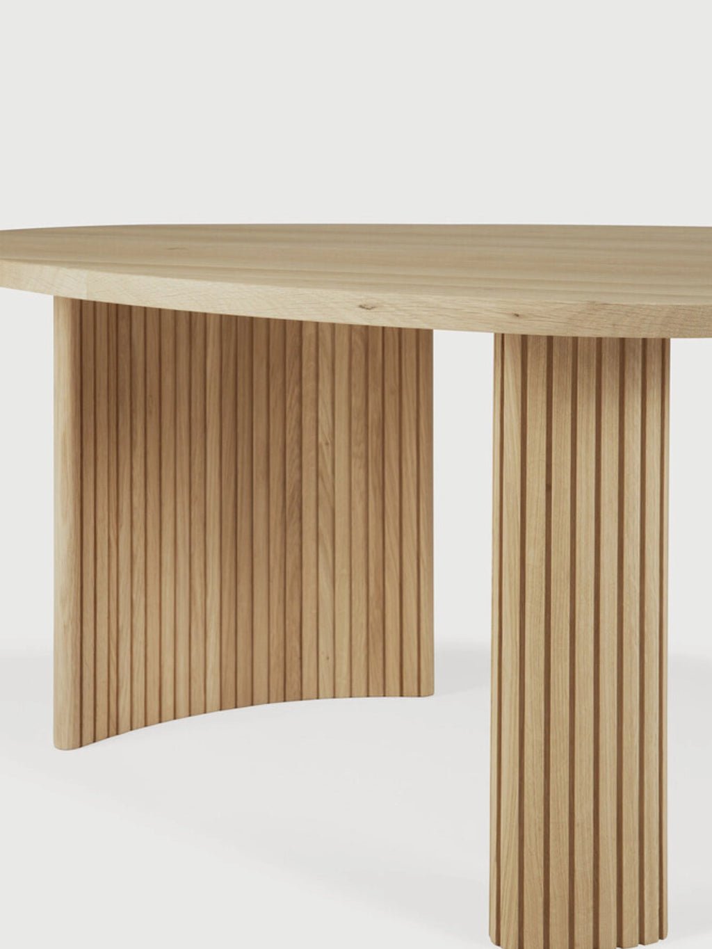 Ethnicraft Boomerang Coffee Table in Oak, 126 cm, showing a detailed close-up of its premium solid oak construction. The image emphasizes the beautiful natural wood grain and the intricate vertical fluting on the sturdy, curved legs, on a white background.