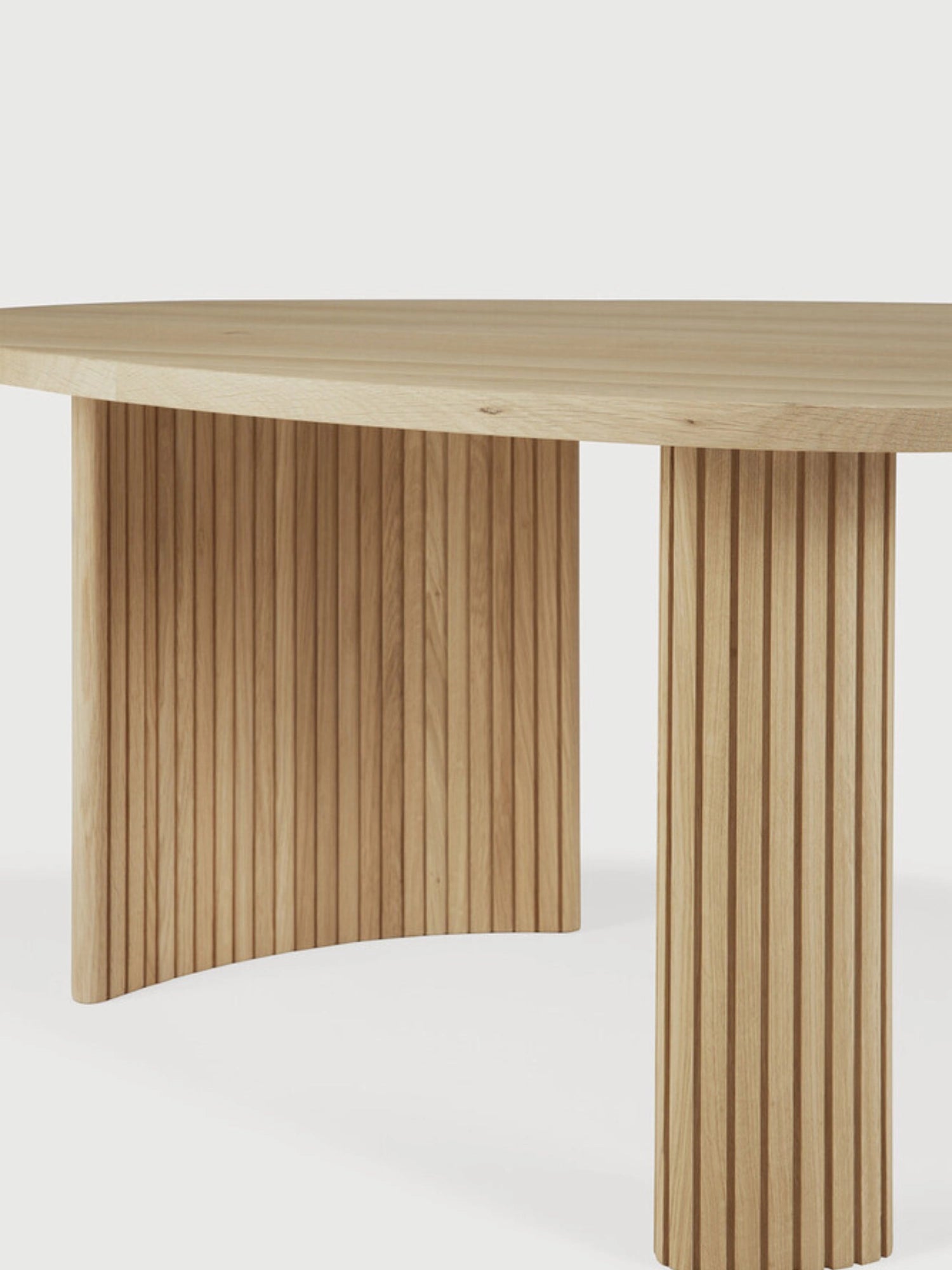 Ethnicraft Boomerang Coffee Table in Oak, 126 cm, showing a detailed close-up of its premium solid oak construction. The image emphasizes the beautiful natural wood grain and the intricate vertical fluting on the sturdy, curved legs, on a white background.