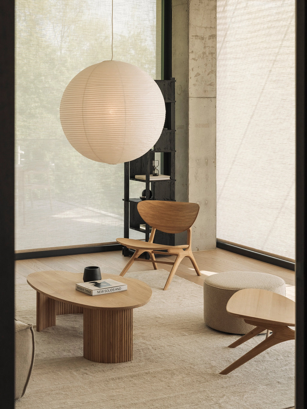 Ethnicraft Boomerang Coffee Table in natural oak, a stylish set in a modern living space with a large paper lantern, light rug, and minimalist wooden furniture.
