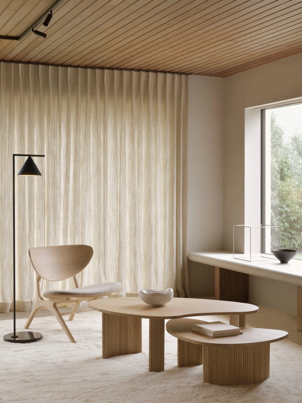 Ethnicraft Boomerang Coffee Table in natural oak, a nested set creating a warm, inviting living room scene with a light wood chair and soft, neutral textiles.