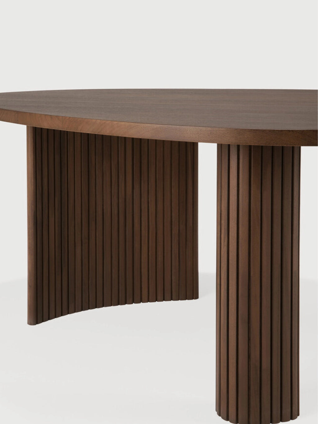 Ethnicraft Boomerang Coffee Table in rich brown teak, a detailed view highlighting the intricate vertical fluting on both the curved and cylindrical support legs, beneath the smooth tabletop, on a white background.
