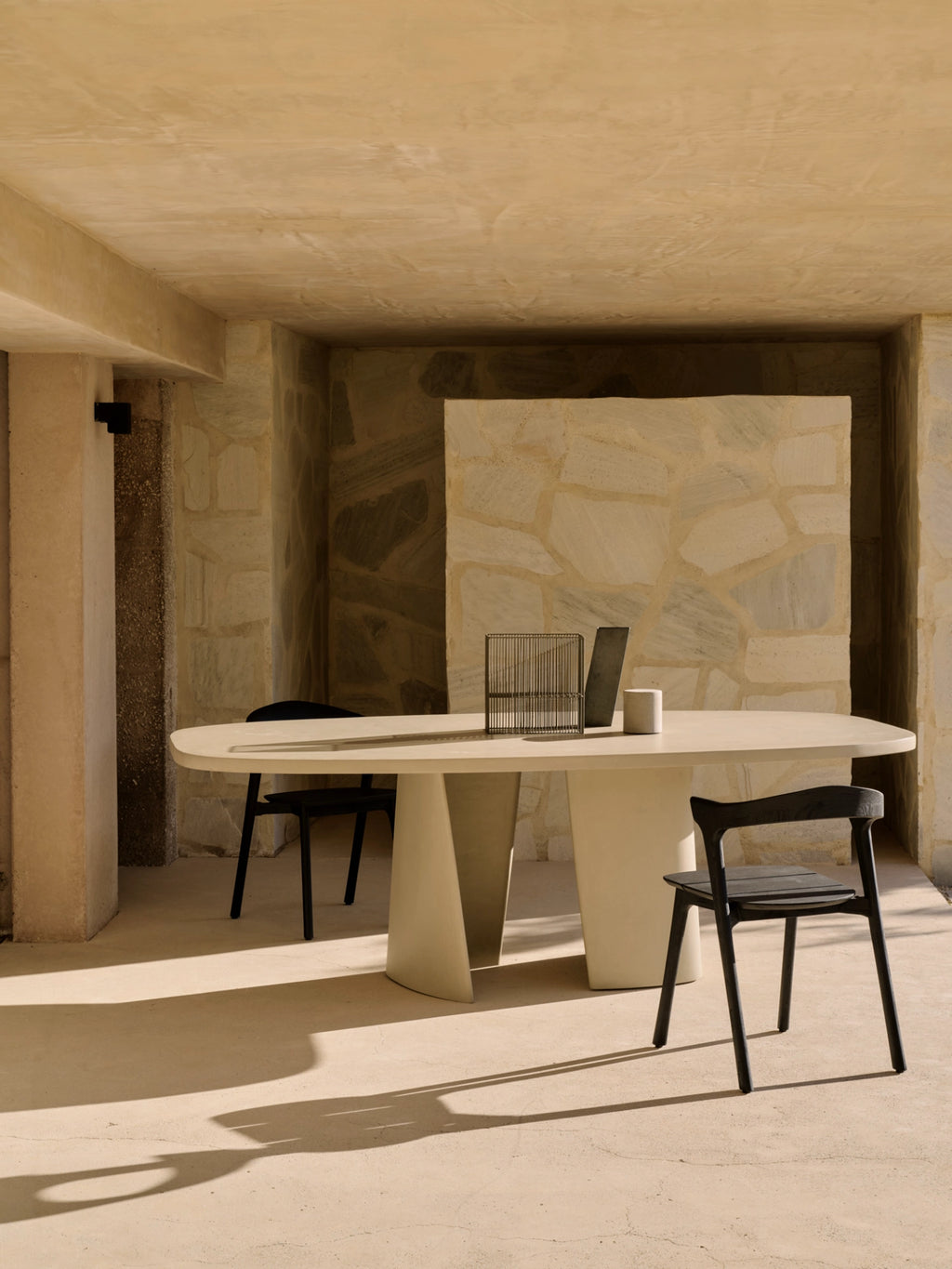 Ethnicraft Canyon Outdoor Dining Table, a modern minimalist outdoor dining table crafted from light-toned, smooth fiber cement with a matte finish. It features a rounded rectangular tabletop supported by two sculptural, trapezoidal pedestal bases, embodying a contemporary brutalist aesthetic. Perfect for a stylish outdoor patio, garden dining area, or modern alfresco living space.