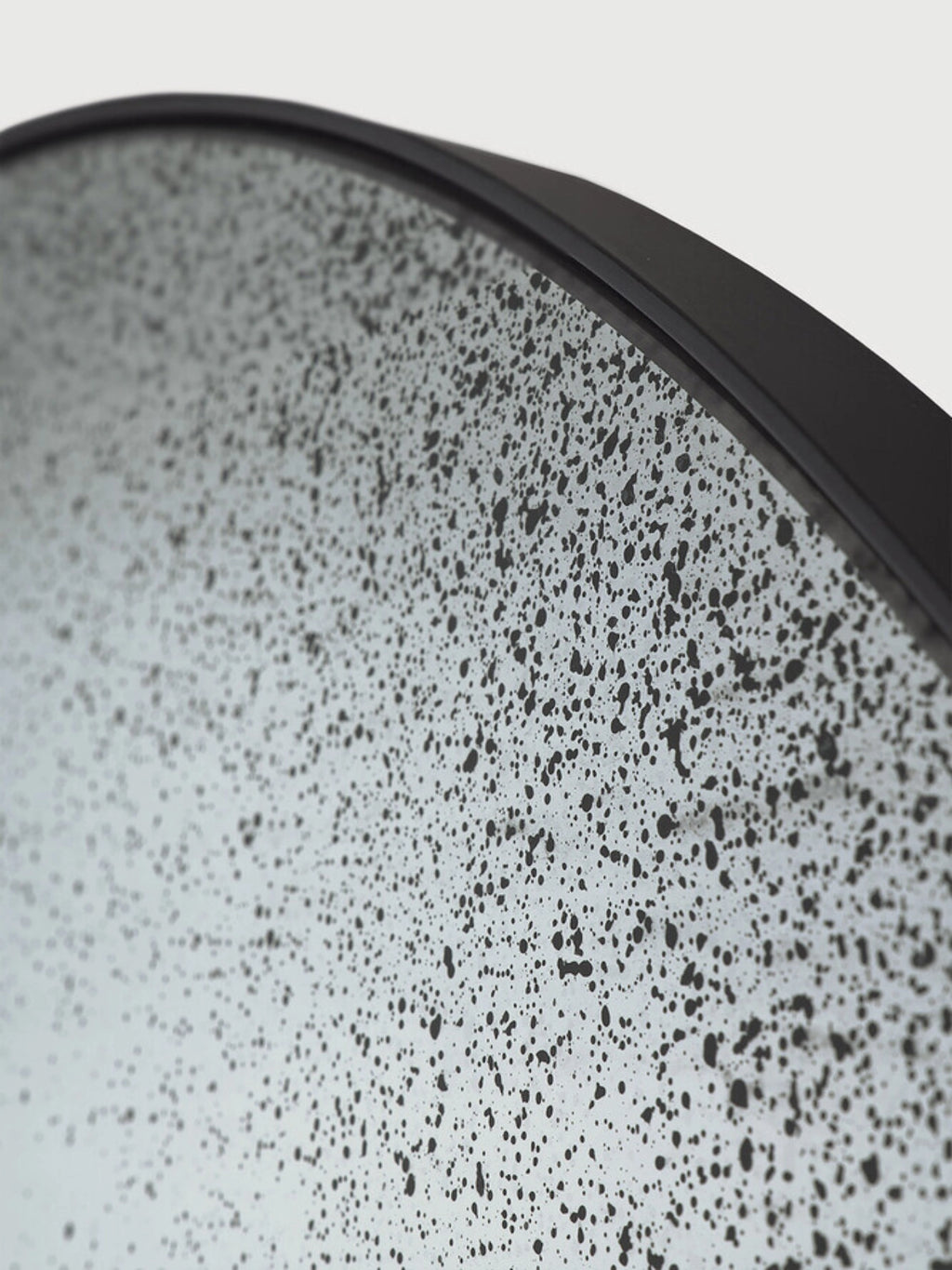 Ethnicraft Clear Gate Floor Mirror, a large round contemporary mirror featuring a sleek matte black metal frame and a distinctive speckled glass surface with an abstract, distressed finish.