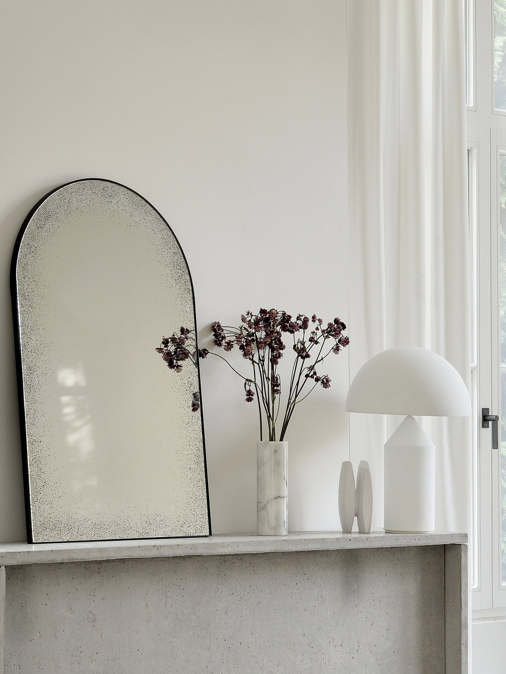 Ethnicraft Clear Gate Wall Mirror, a striking arched mirror featuring a slim black metal frame and beautifully antiqued, distressed mirror glass with a speckled finish. This large decorative mirror offers a modern minimalist aesthetic with a touch of vintage appeal, perfect as a statement piece for contemporary living rooms, industrial chic entryways, or elegant bedrooms.