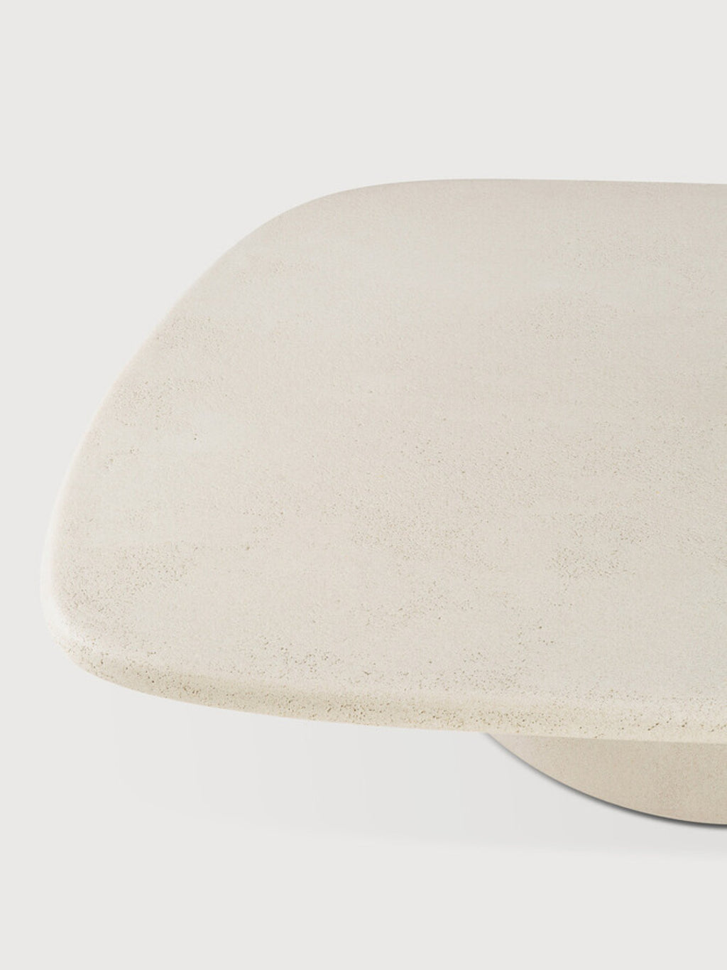 Ethnicraft Elements Coffee Table, a close-up of the pebble-shaped top's surface, revealing the fine, textured grain of the premium light beige microcement, offering a tactile and modern aesthetic.