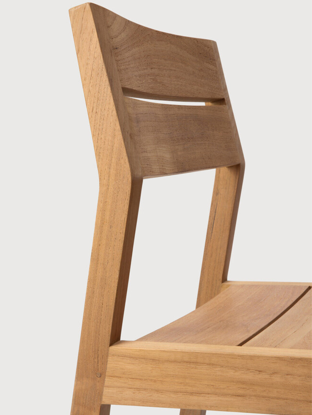 Ethnicraft EX1 Outdoor Dining Chair, a modern outdoor dining chair crafted from durable solid teak wood with a warm natural light brown finish and visible wood grain. It features a gently curved backrest with a horizontal slat detail, clean lines, and a slatted seat. Perfect for contemporary outdoor dining areas, patios, or garden spaces.