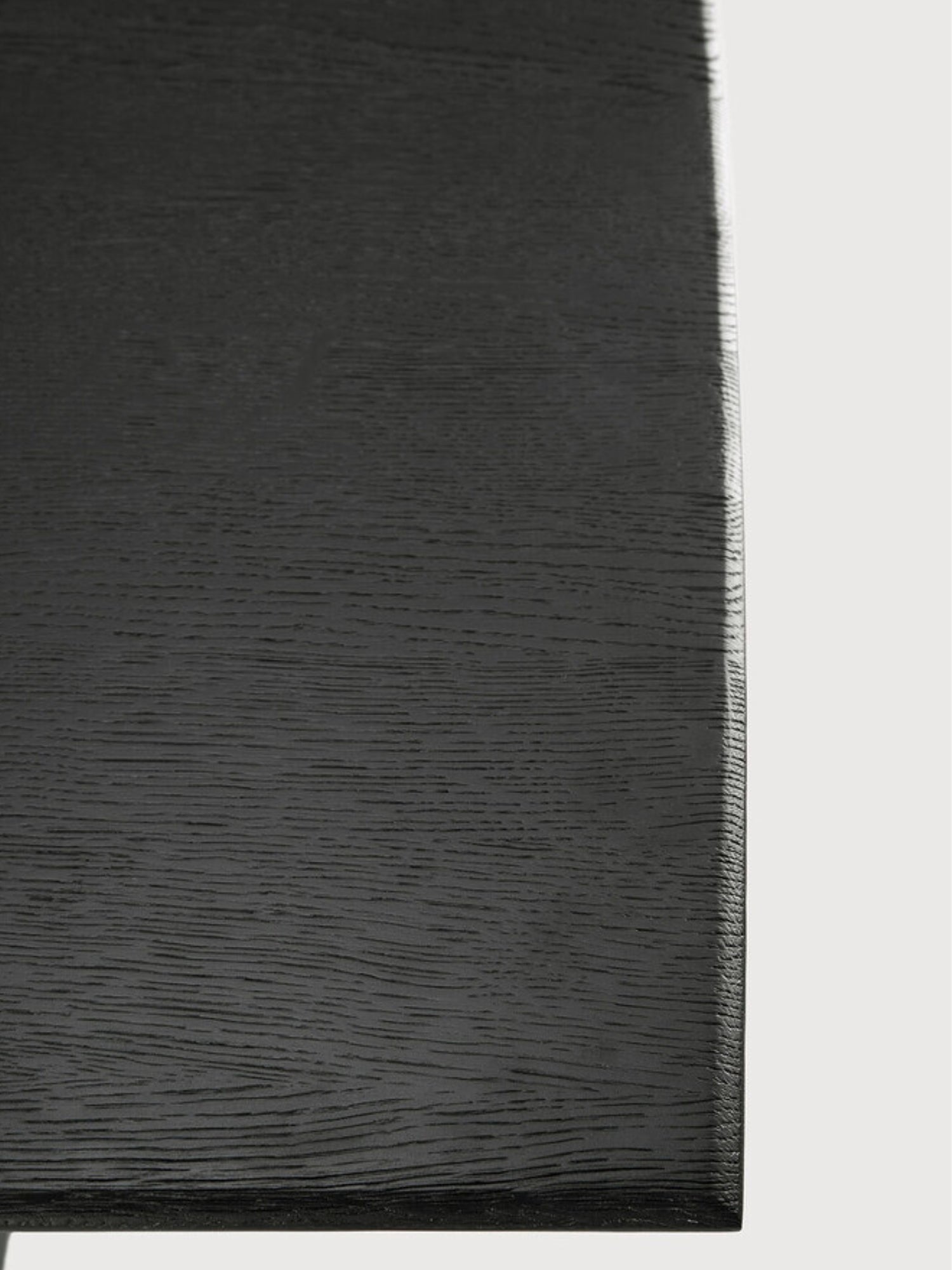 Ethnicraft Geometric Dining Table, a contemporary solid oak dining table featuring a deep matte black finish with a visible textured wood grain, showcasing clean geometric lines and a modern minimalist aesthetic. This striking dark wood dining table is perfect for sophisticated dining rooms or a chic modern kitchen.