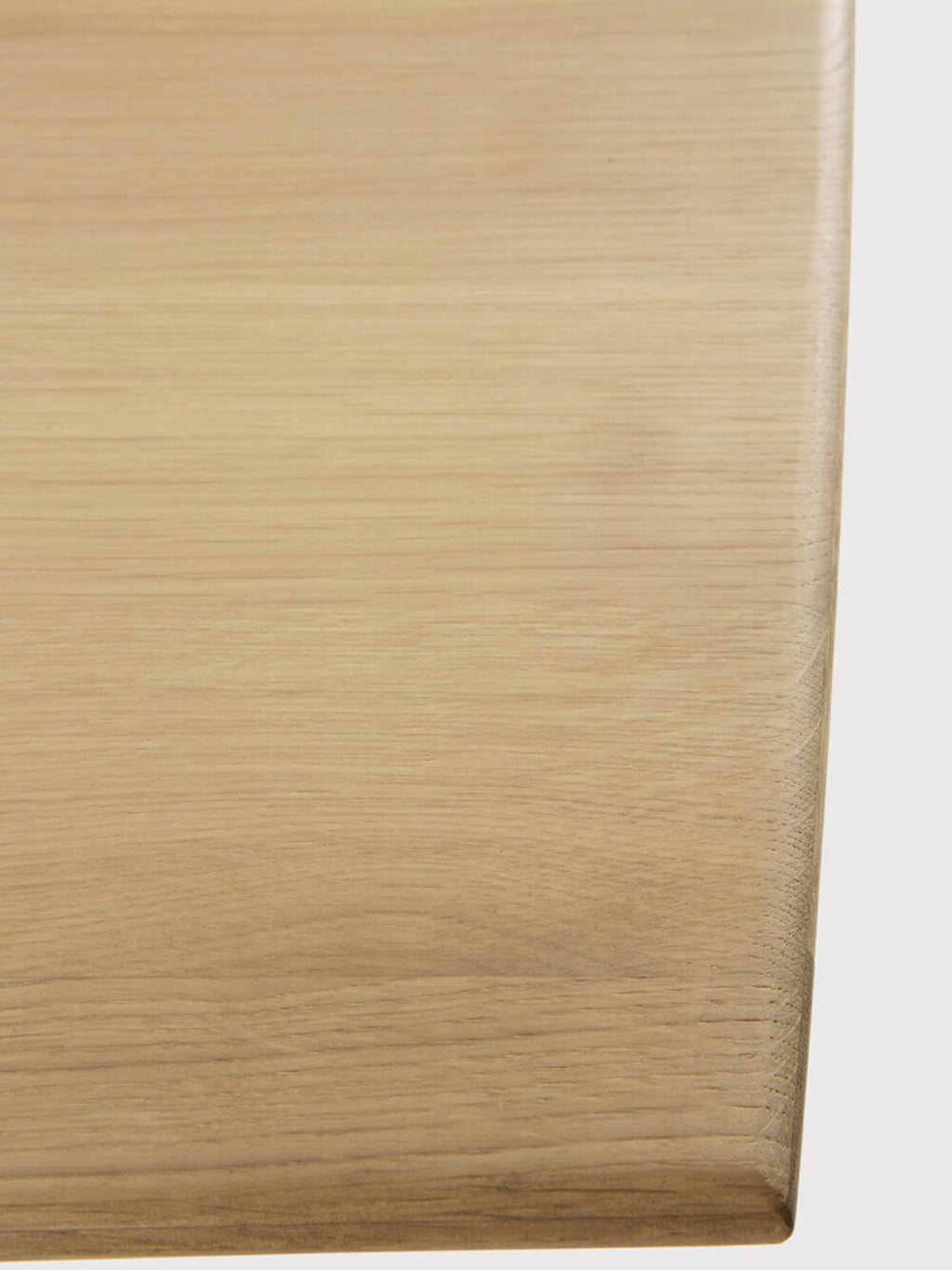 Ethnicraft Geometric Dining Table, a modern solid oak dining table showcasing a light natural oak finish with subtle wood grain texture and a smooth, softly rounded edge. This contemporary blonde wood dining table is ideal for Scandinavian dining rooms and minimalist interiors.
