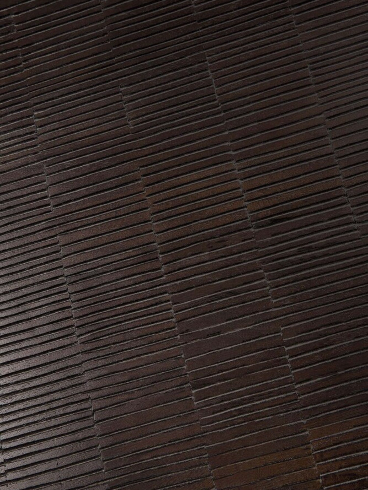 Ethnicraft Grooves Coffee Table, a detailed close-up of the off-black teak tabletop, showcasing the exquisite, hand-carved linear patterns and rich, dark wood grain texture.