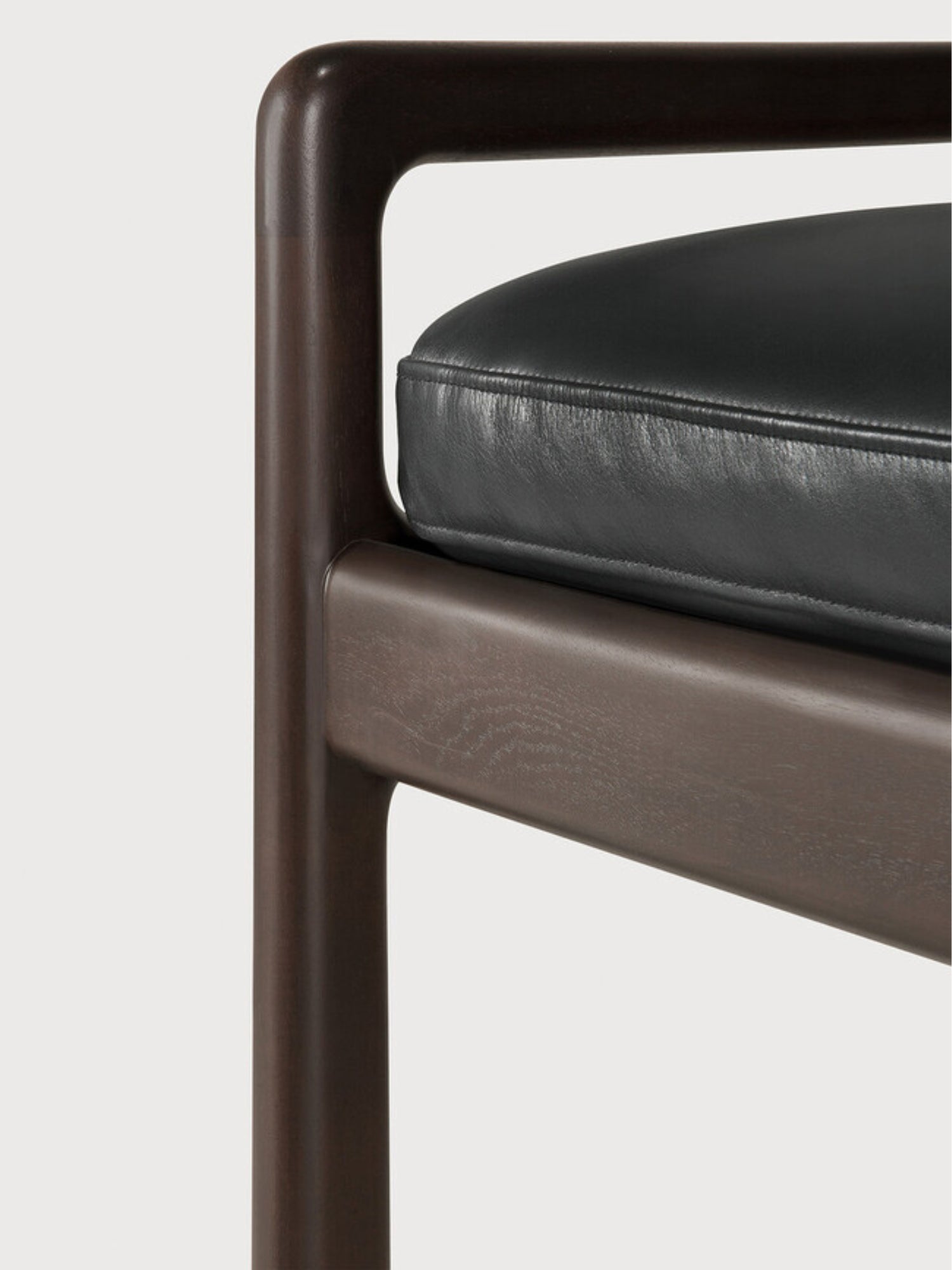 Ethnicraft Jack Bench, a close-up detail of the mahogany dark brown wooden frame and the sleek black leather cushion, highlighting the smooth finish and luxurious feel.