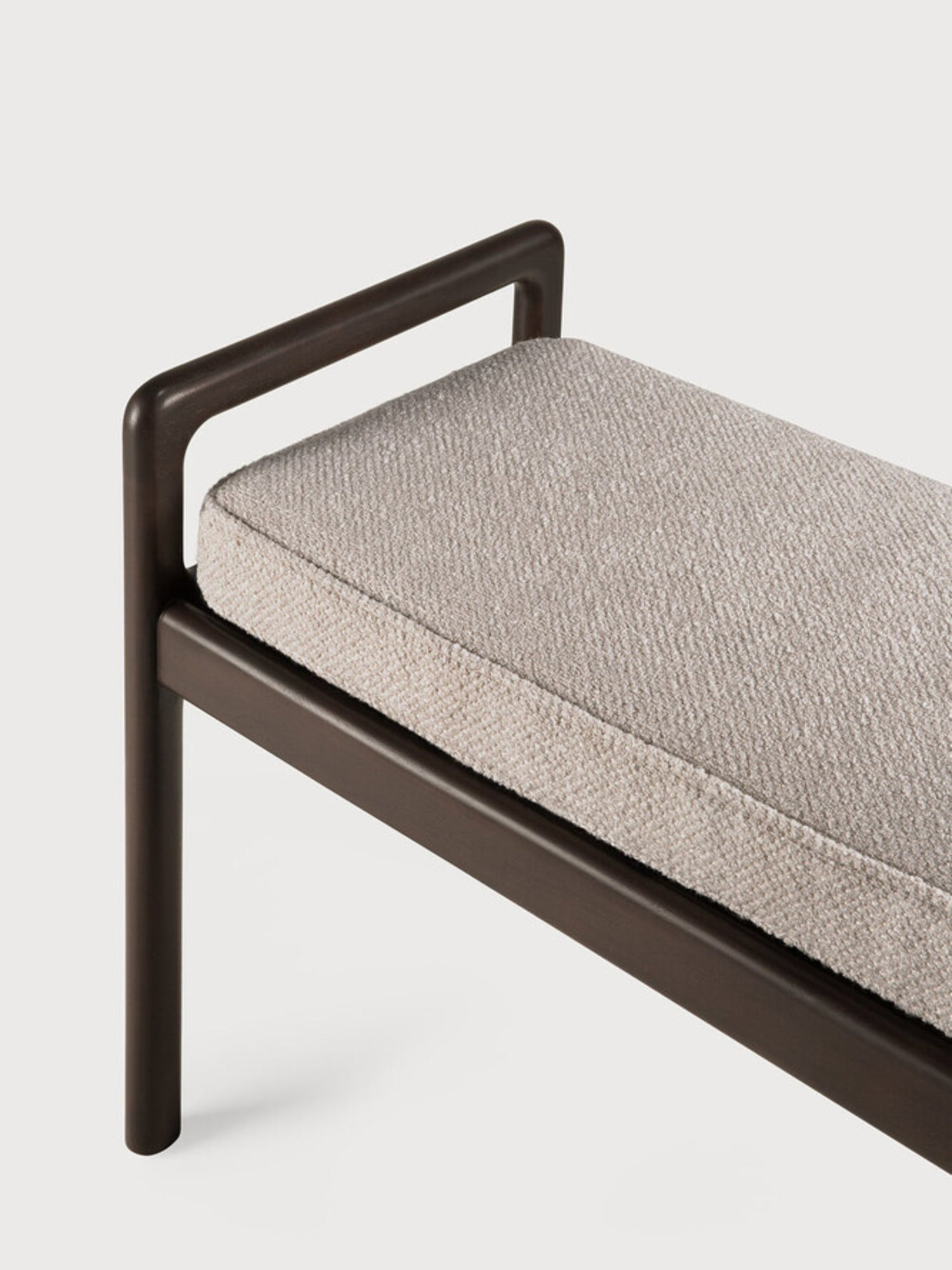 Ethnicraft Jack Bench, a close-up detail of the mahogany dark brown wooden frame and the plush ivory fabric cushion, highlighting the smooth, rounded edges and fine craftsmanship.