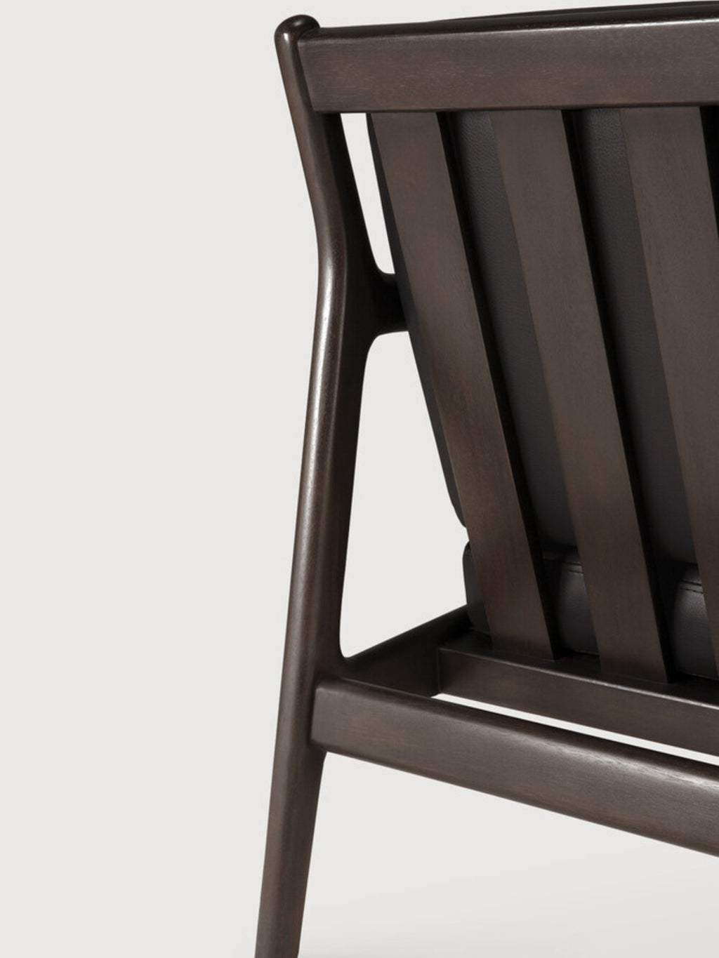 Ethnicraft Jack Lounge Chair, a modern lounge chair crafted from a dark brown solid wood frame with elegant curved lines and a distinctive slatted backrest, featuring plush black leather upholstery visible between the slats. This contemporary design piece is perfect for a sophisticated living room, stylish reading nook, or a mid-century inspired home office.
