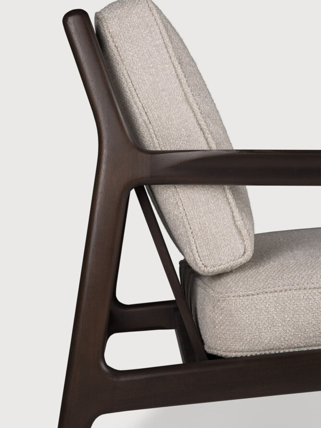 Ethnicraft Jack Lounge Chair, a sophisticated mid-century modern armchair featuring a dark solid wood frame with elegantly curved, organic lines and smooth finish. It's upholstered in a plush, light beige textured fabric, likely a bouclé, for comfortable seating. Perfect as a Scandinavian accent chair or contemporary living room furniture for cozy reading nooks.