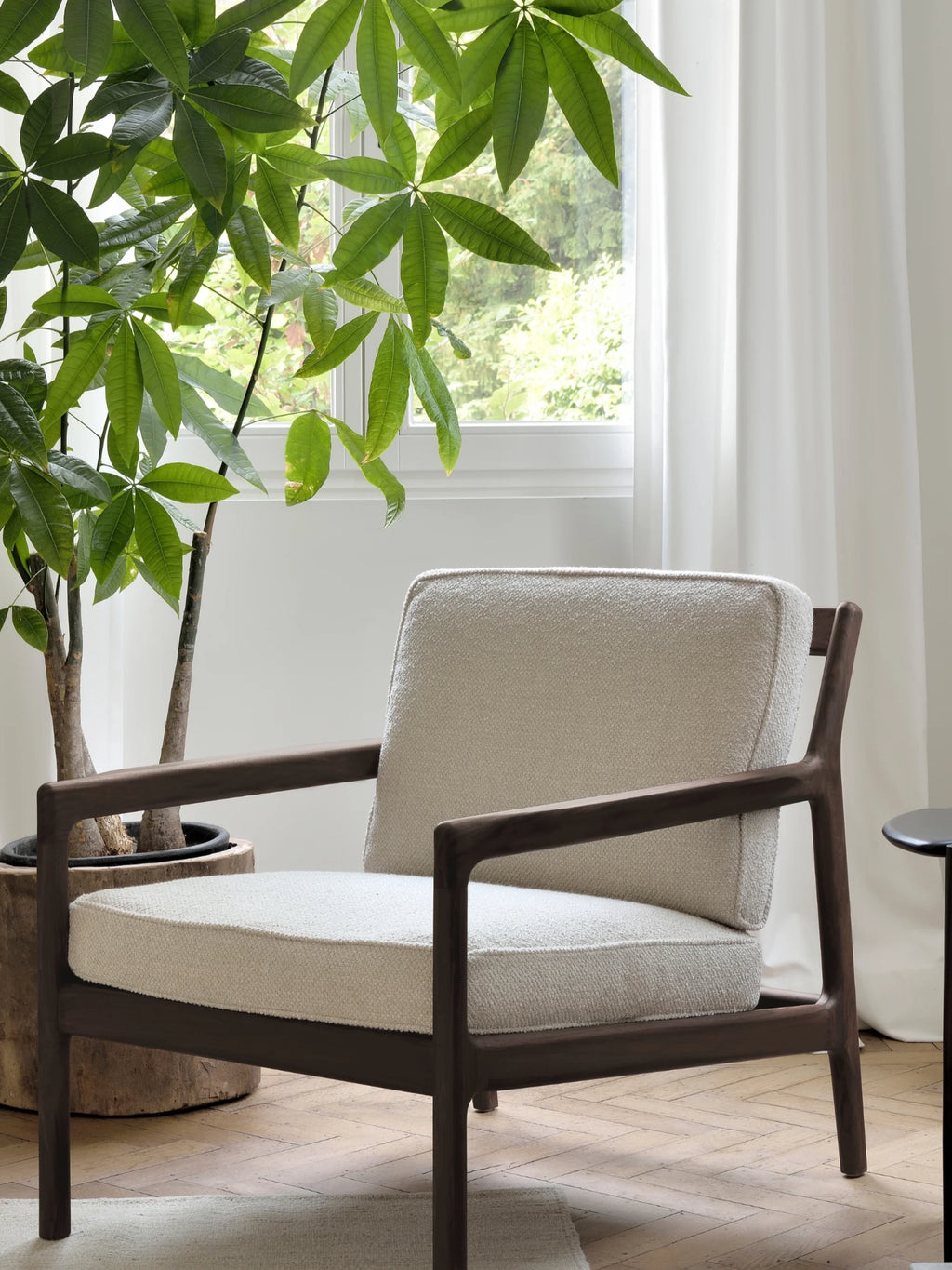 Ethnicraft Jack Lounge Chair, a modern minimalist lounge chair featuring a dark solid wood frame with clean lines and gently rounded armrests, paired with plush cream bouclé-style fabric cushions. This contemporary accent chair offers comfortable seating, perfect for a sophisticated living room, cozy bedroom reading nook, or stylish home office.