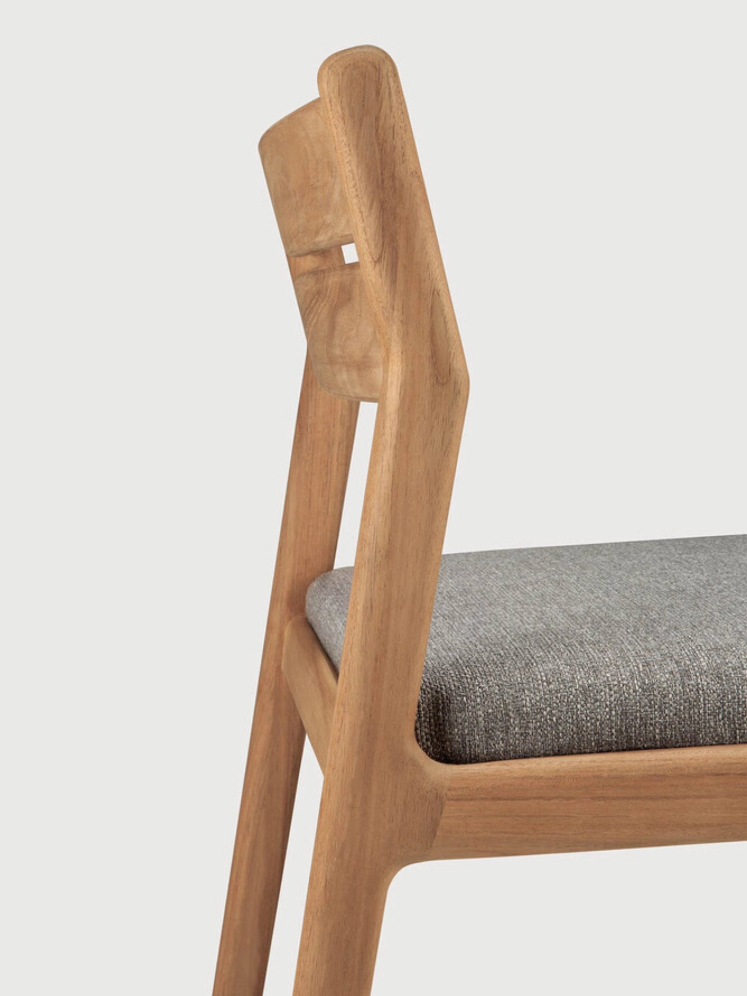 Ethnicraft Jack Outdoor Dining Chair Without Armrest, a modern minimalist dining chair crafted from solid natural teak wood with a warm, visible grain and a comfortable grey fabric upholstered seat. Its clean Scandinavian design features a gently angled backrest with a subtle cutout detail, perfect for contemporary outdoor dining areas or stylish patio seating.