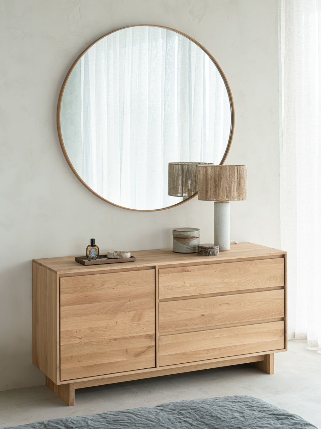 Ethnicraft Layers Wall Mirror, a large round wall mirror featuring a minimalist design with a sleek solid oak frame in a warm natural wood finish. Its clean circular shape and smooth texture make it an ideal contemporary statement piece for modern interiors. Perfect for Scandinavian bedrooms, organic modern living rooms, or an inviting entryway.
