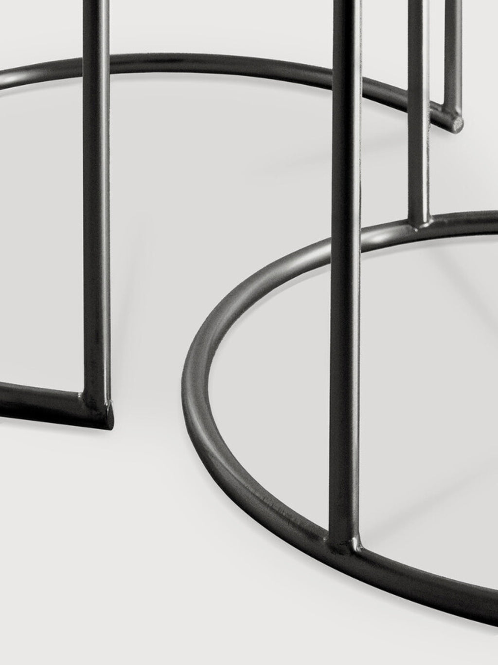Ethnicraft Nesting Coffee Table Set, close-up detail of the sleek black metal bases, highlighting the minimalist, sturdy circular design and modern aesthetic on a white background.