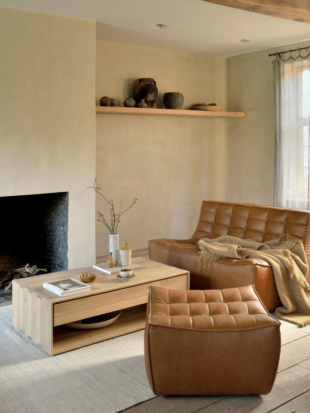Ethnicraft Nordic Coffee Table, a modern 120cm oak coffee table with a clean, minimalist design, featuring a spacious top and open shelf, styled in a cozy living room with a brown leather sofa and fireplace.
