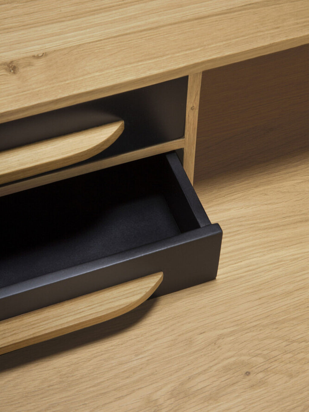 Ethnicraft Origami Desk in black oak, a detailed close-up showing the smooth, dark wood grain and the innovative, curved pull-out drawers with black interiors, highlighting premium craftsmanship.