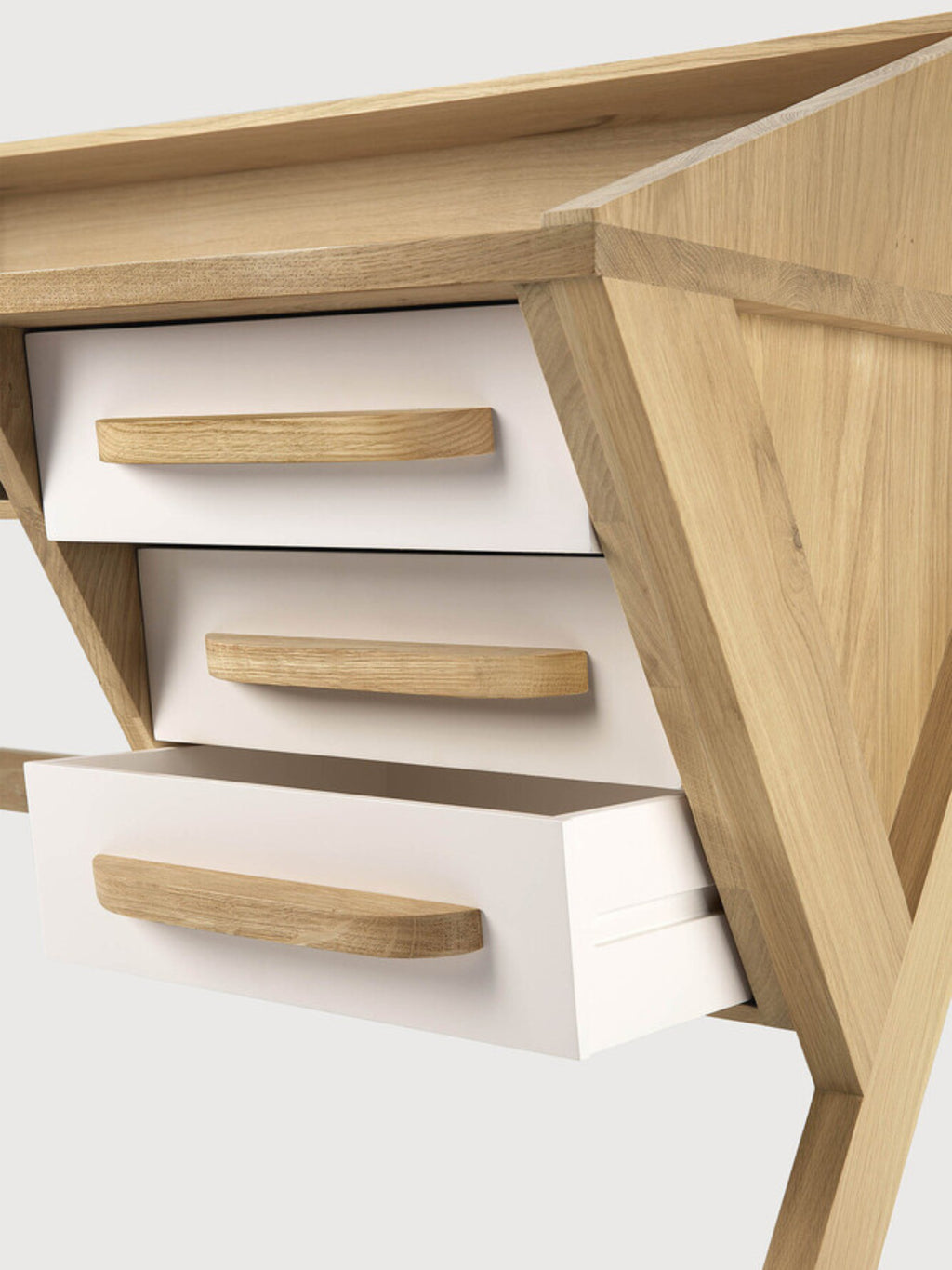 Ethnicraft Origami Desk in white oak, a detailed view of the desk's side, showcasing the three integrated white drawers with natural oak handles and the unique angled leg structure, on a white background.