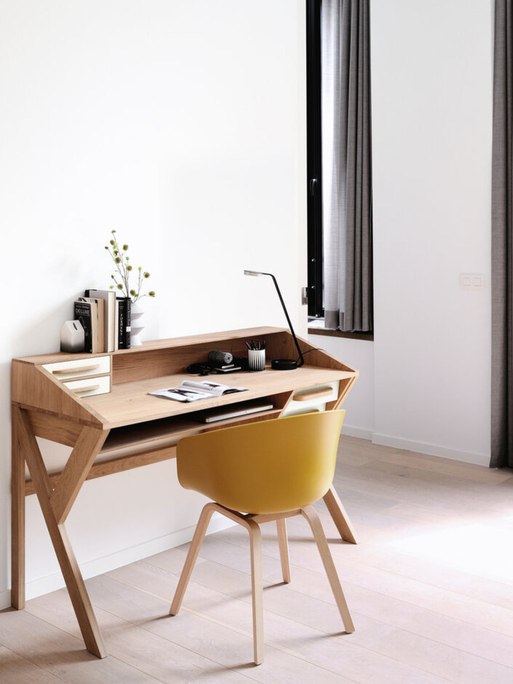 Ethnicraft Origami Desk in white oak, a contemporary and elegant writing desk featuring a light wood finish, integrated storage, and clean lines, presented in a bright, airy room with a yellow chair.