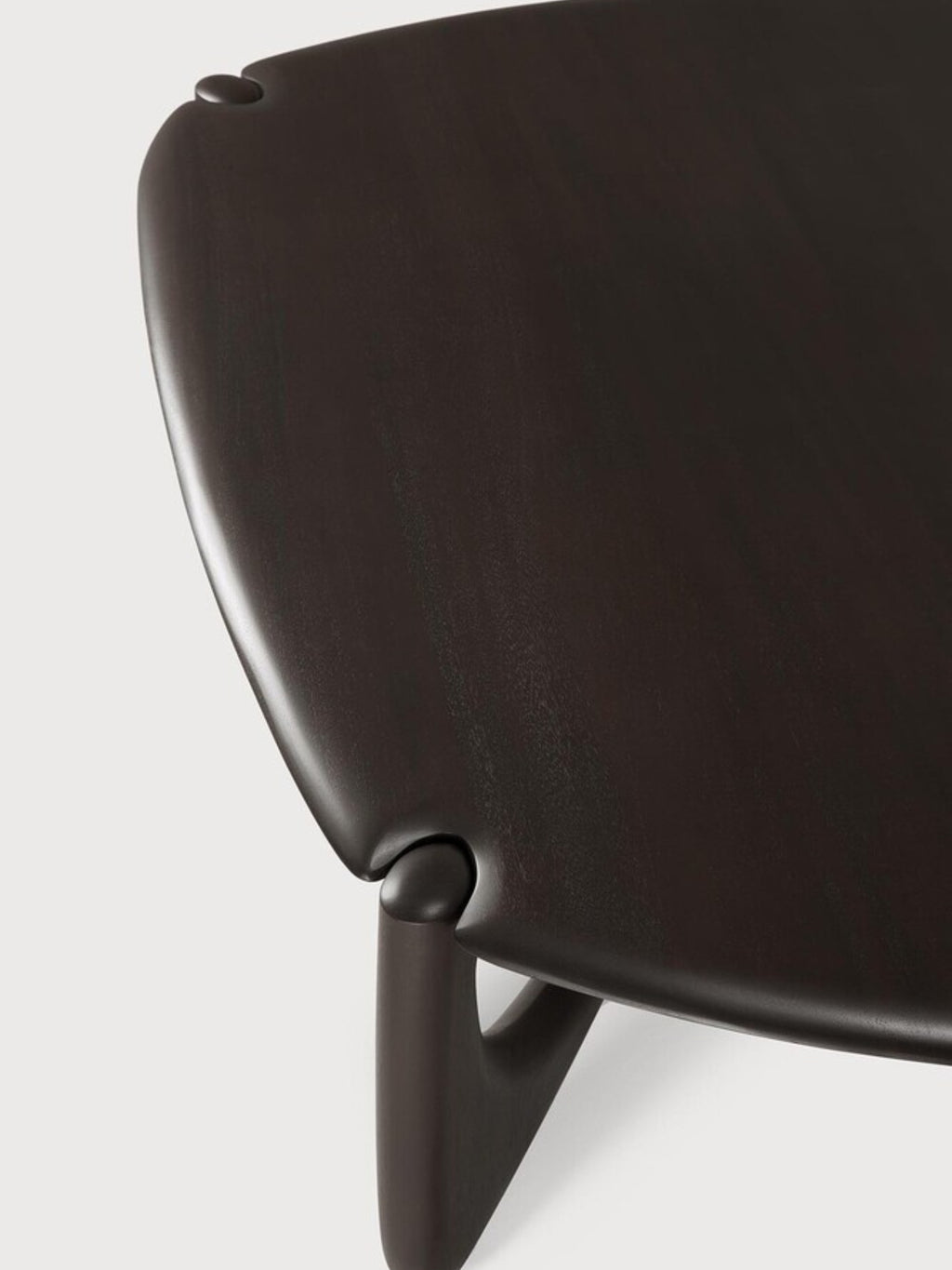 Ethnicraft PI Coffee Table in Mahogany Dark Brown, Pebble shape. Close-up of the table's side, emphasizing the rich, dark brown mahogany wood finish, the gently curved edges, and the sculptural, integrated leg design, on a white background.