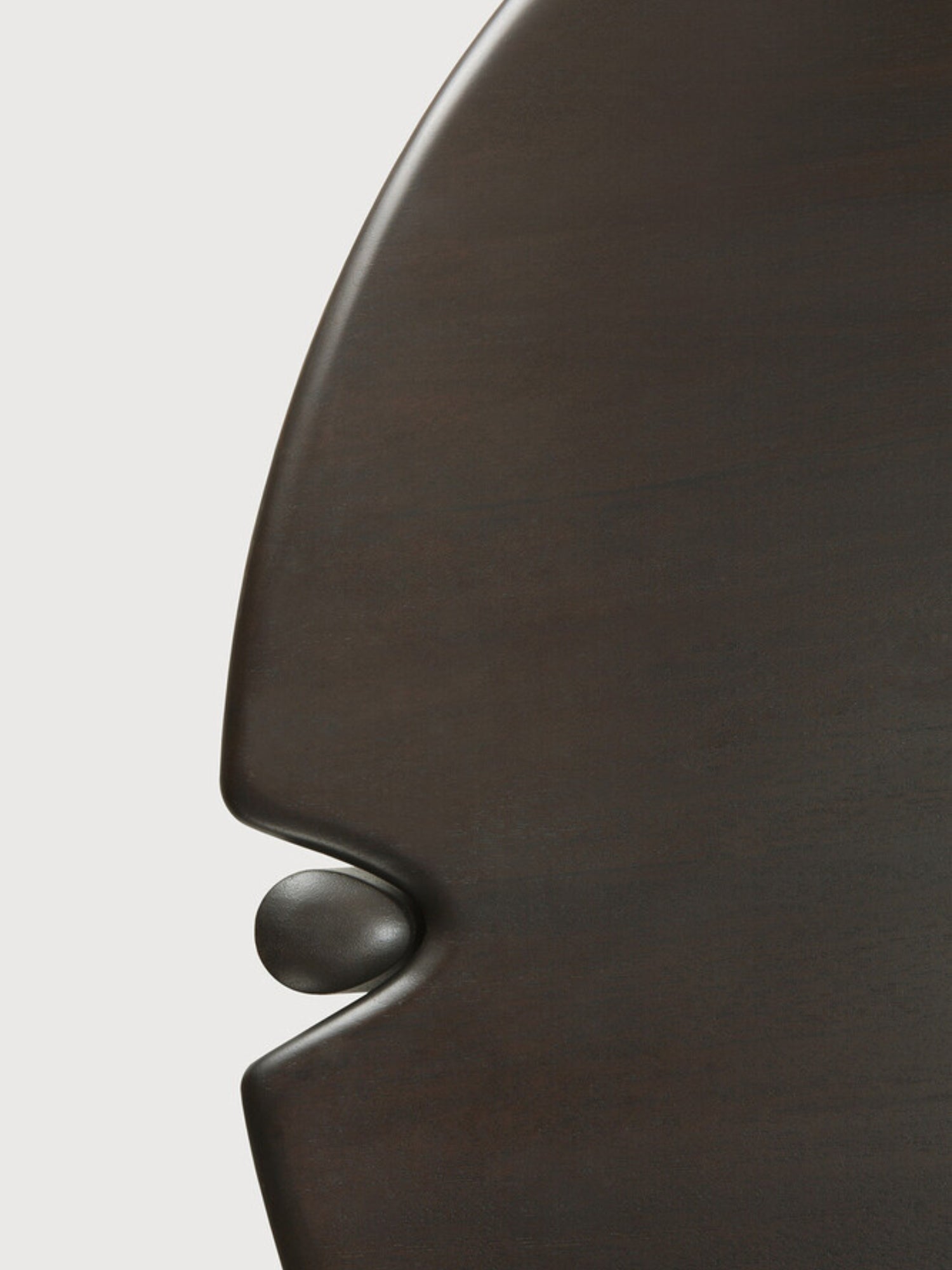 Ethnicraft PI Coffee Table, an extreme close-up of the dark brown mahogany round wooden coffee table, showcasing the intricate detail of its tabletop edge and the subtle, elegant connection to its base.