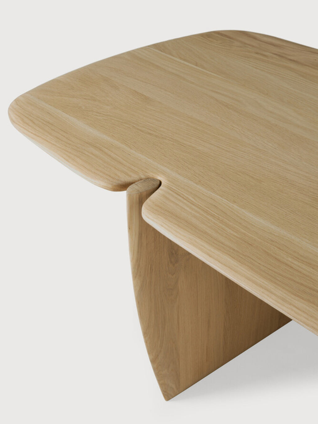 Ethnicraft PI Coffee Table in natural oak, rectangular shape. A close-up detail shot reveals the smooth, light wood grain and the seamless, elegant joint where the tabletop meets the leg, displayed on a white background.